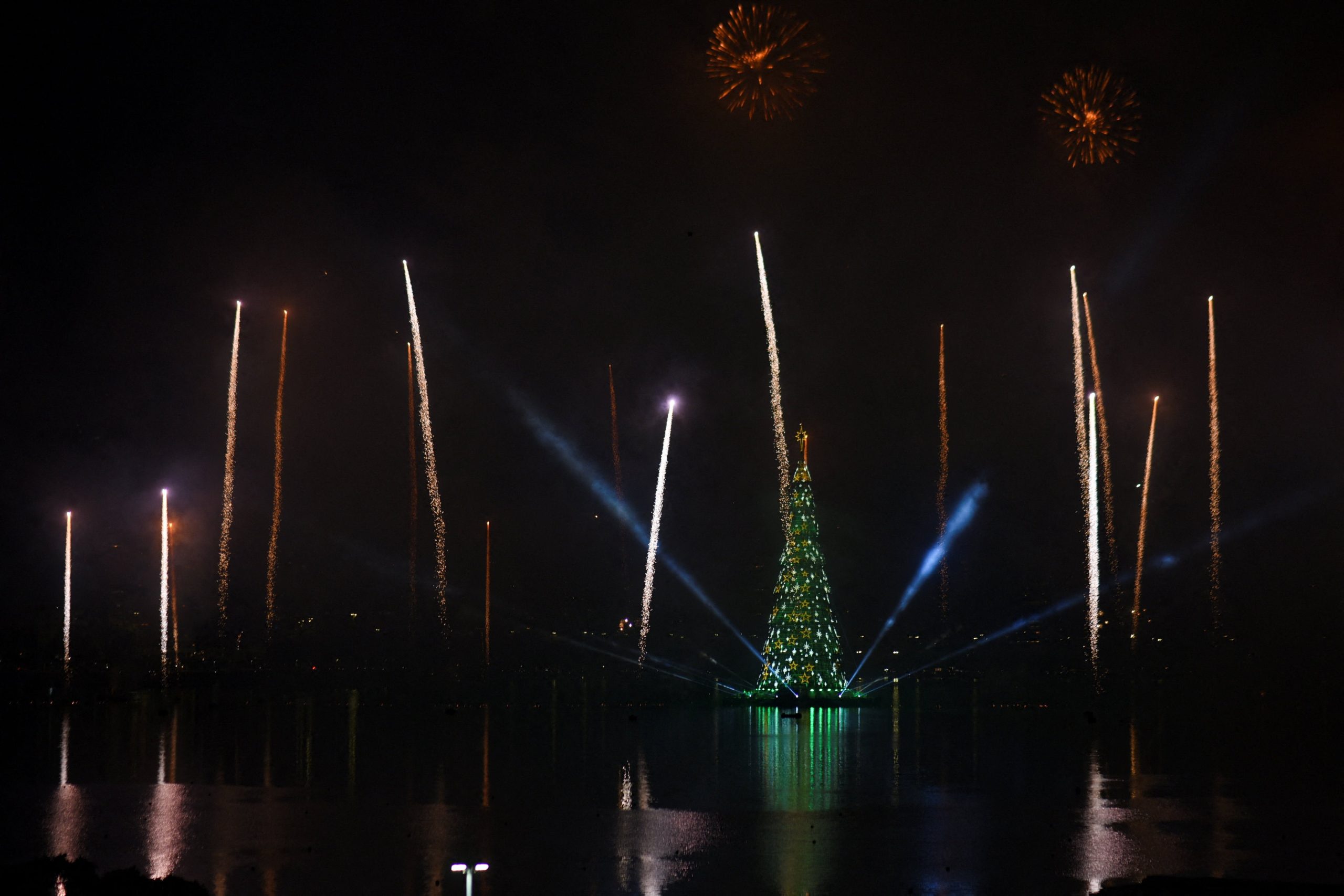 Los fuegos artificiales iluminan el cielo mientras se ilumina un árbol de Navidad durante una ceremonia en el lago Rodrigo de Freitas en Río de Janeiro, Brasil.