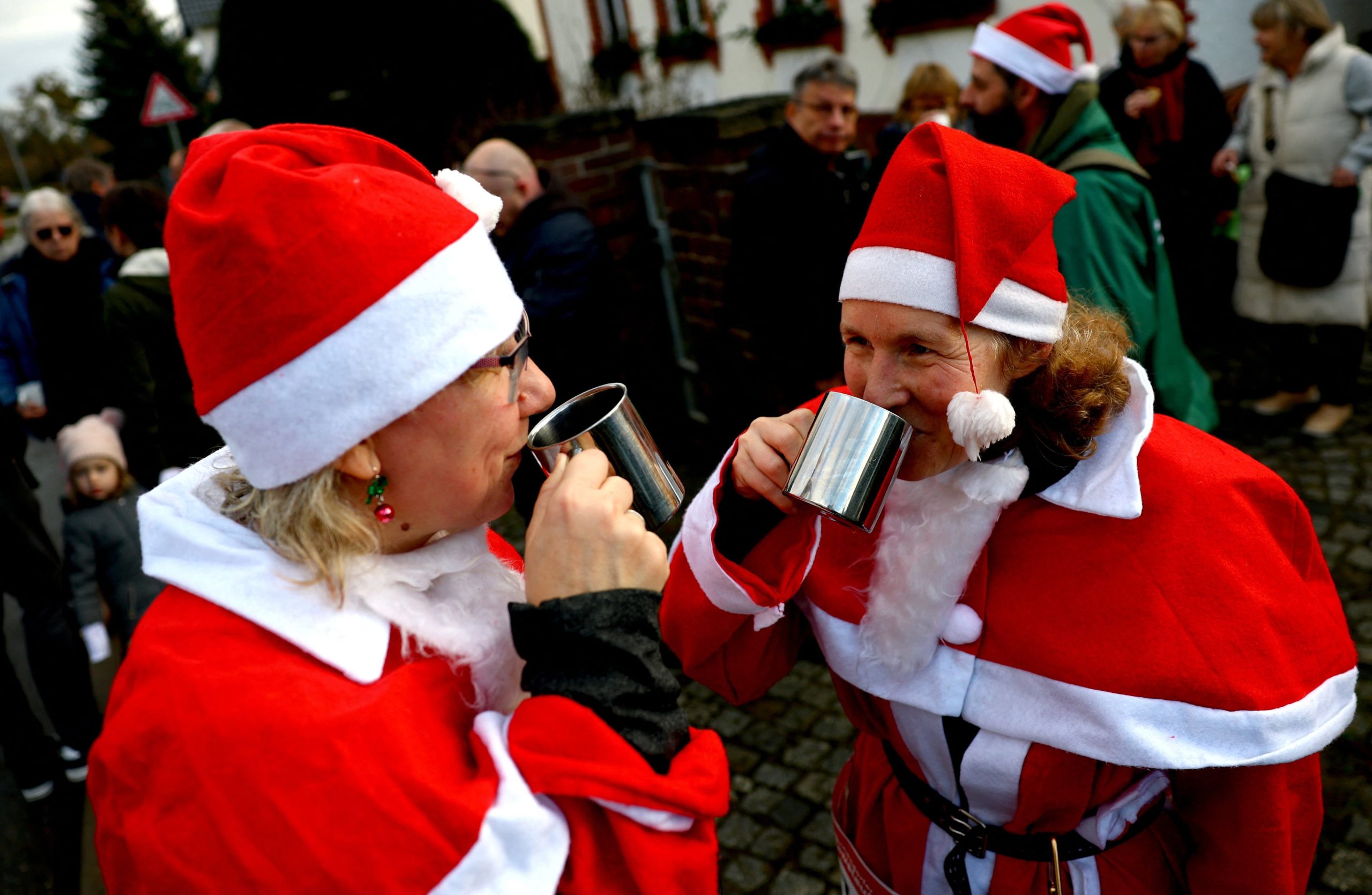 Personas vestidas de Papá Noel se toman un descanso de la carrera para beber un vino caliente mientras participan en la 'Nikolauslauf' anual en Michendorf, Alemania.