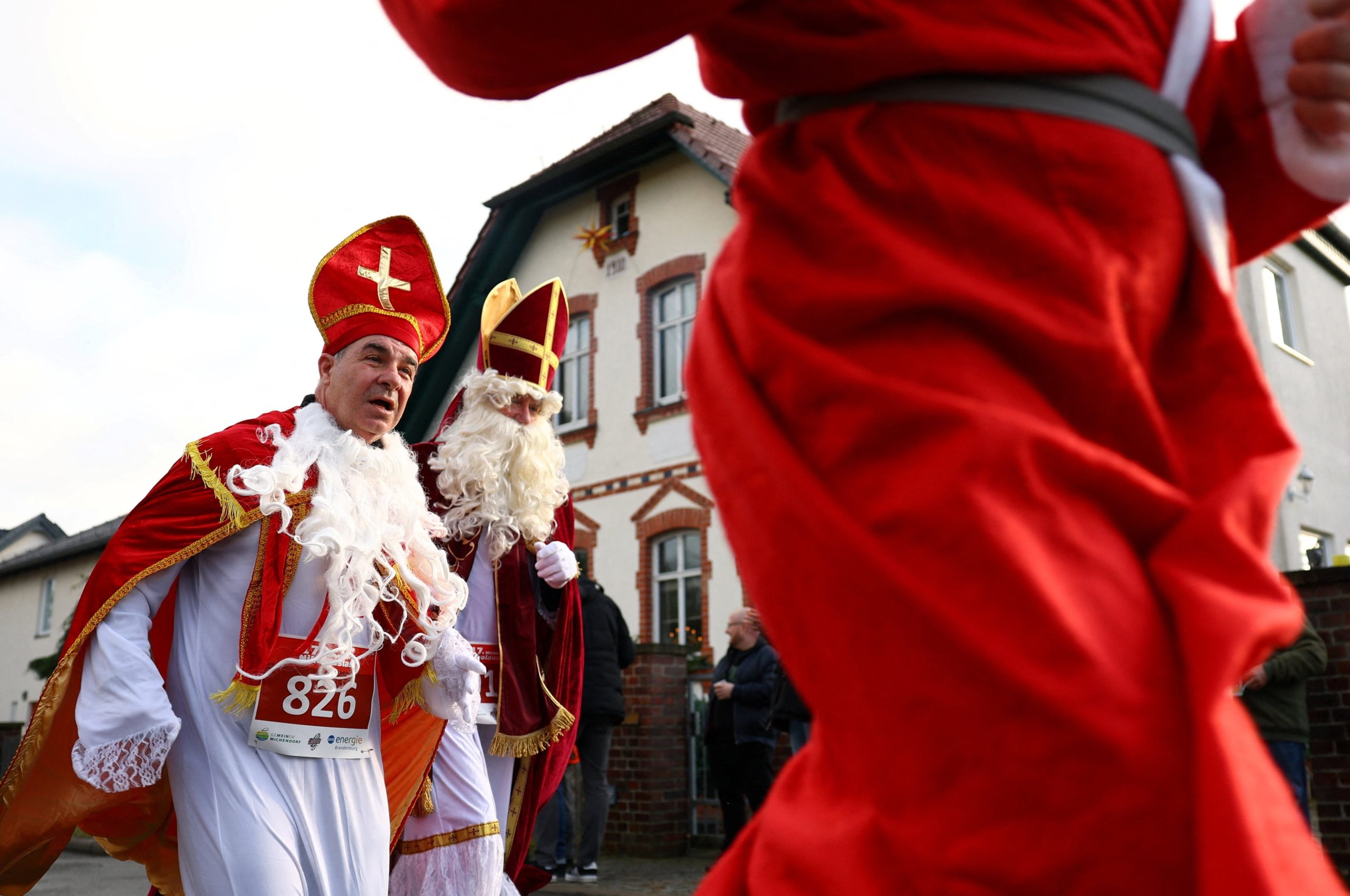 Personas vestidas de San Nicolás corren por las calles mientras participan en la 'Nikolauslauf' anual en Michendorf, Alemania.
