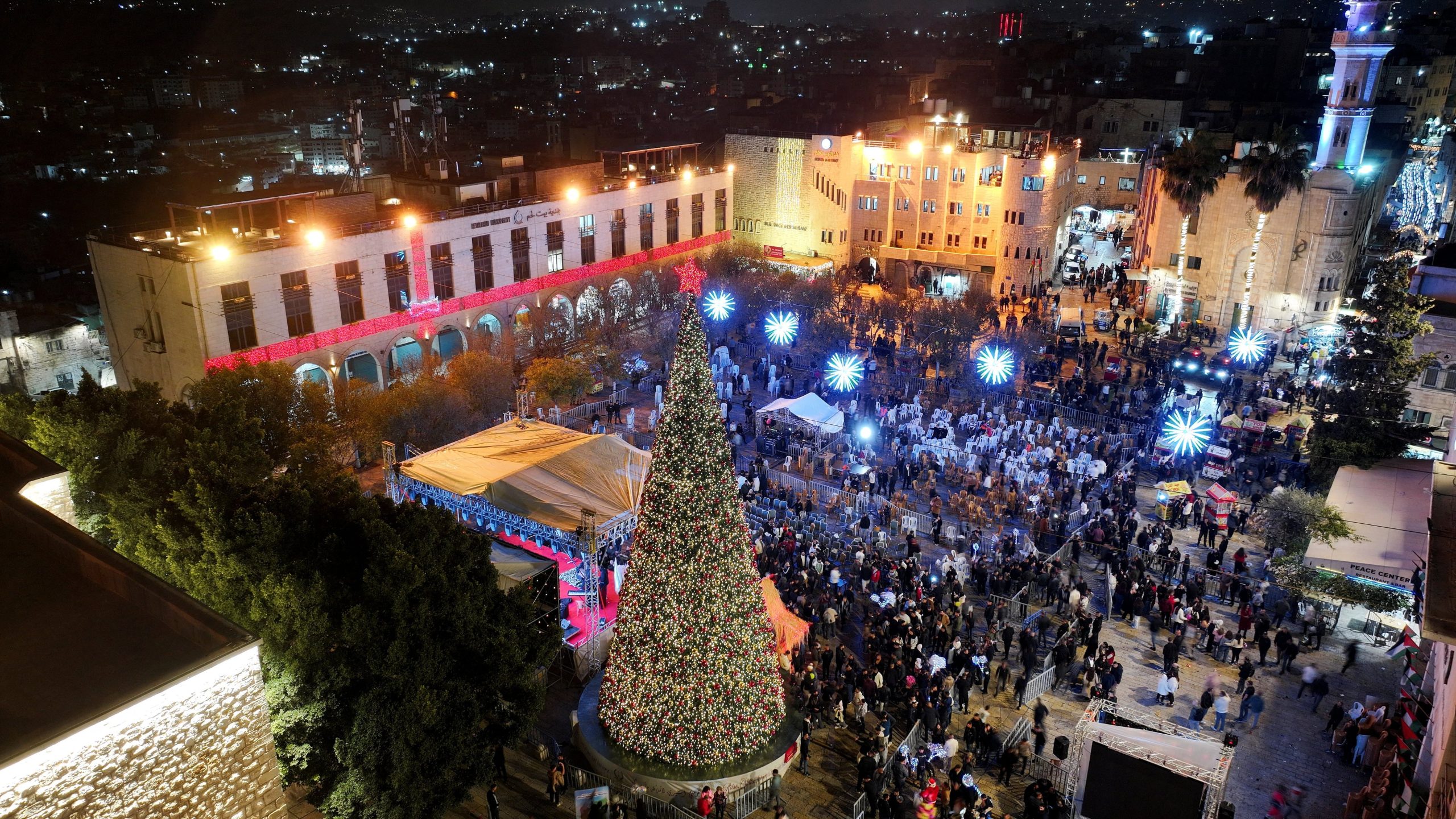 Una vista aérea de palestinos iluminando un árbol de Navidad en la Plaza del Pesebre, afuera de la Iglesia de la Natividad en Belén