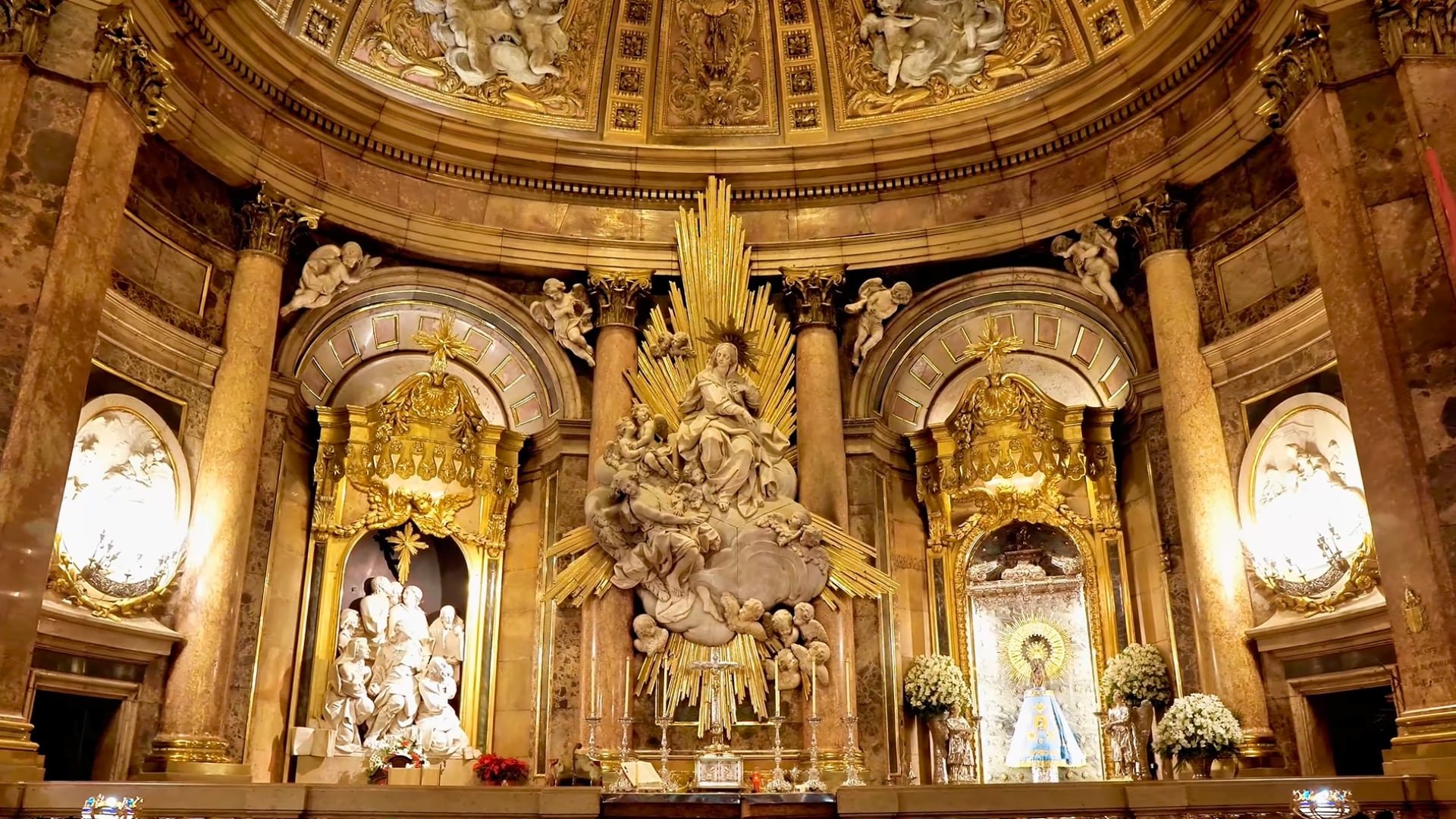 La Basílica de Nuestra Señora del Pilar en Zaragoza alberga la participación española, con tomas aéreas del templo y del río Ebro, y escenas de los Infanticos en el camerino de la Virgen. - Crédito: Coro de Niños Acólitos de Huancavelica