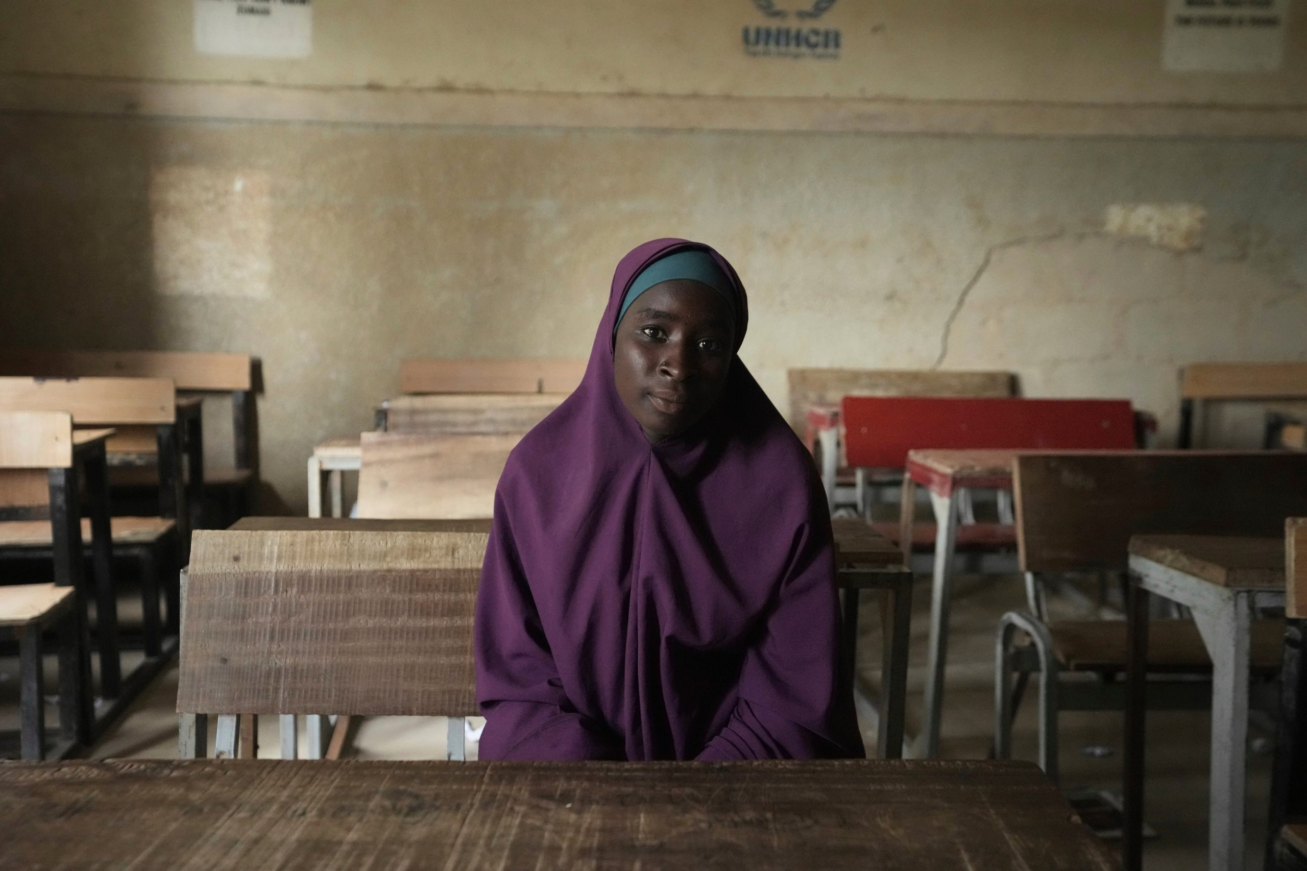 Ramatu Usman, que fue expulsada de la escuela de la Future Prowess Islamic Foundation, posa para una fotografía en un pupitre dentro de su antigua clase, en Maiduguri, Nigeria, el 24 de julio de 2025. (AP Foto/Sunday Alamba)