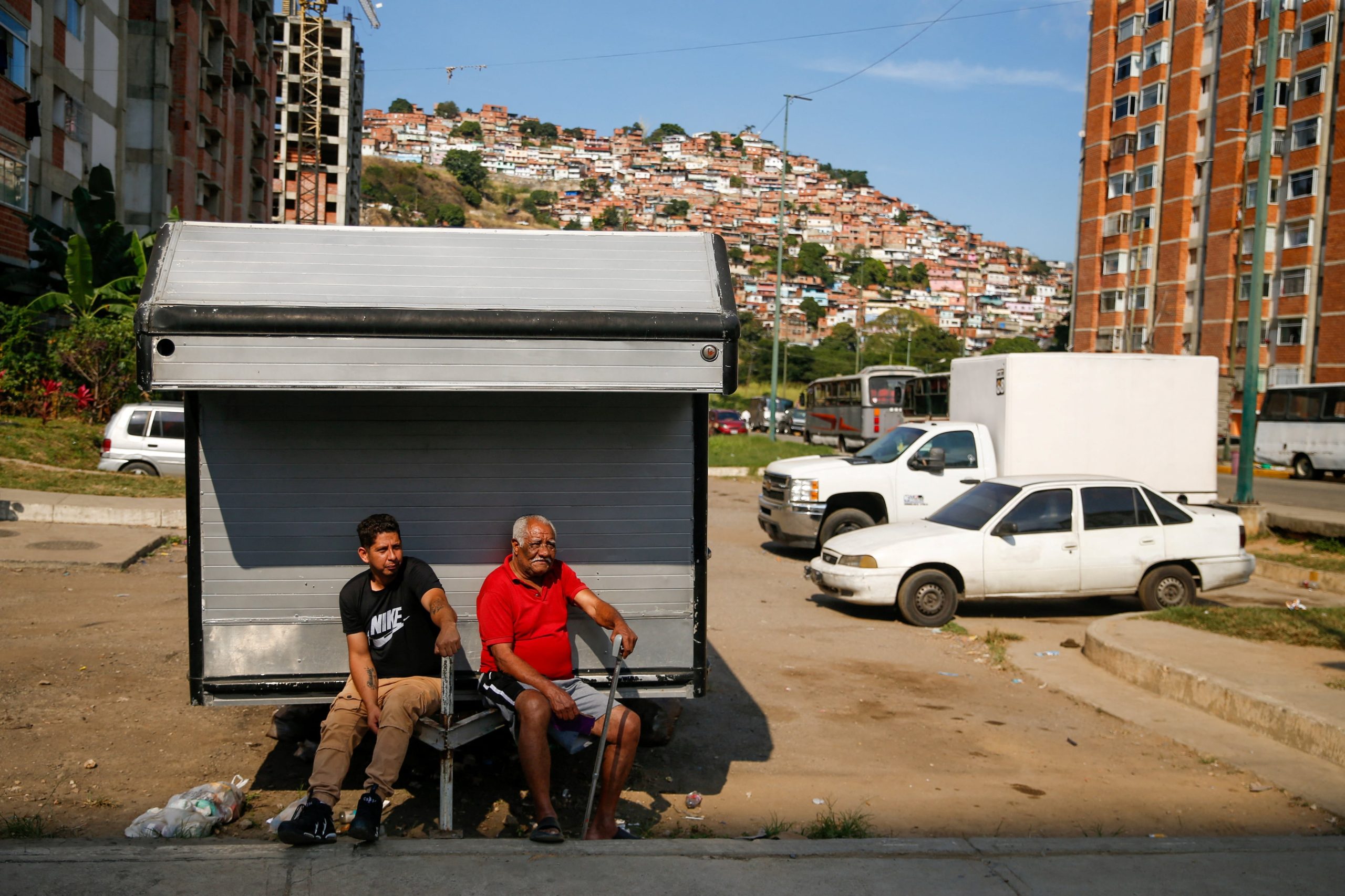 Hombres se sientan afuera, mientras varios vecindarios permanecen sin electricidad después de que Estados Unidos lanzó un ataque contra Venezuela, capturando a su presidente Nicolás Maduro y su esposa Cilia Flores, en Caracas, Venezuela, el 4 de enero de 2026 (REUTERS/Leonardo Fernandez Viloria)