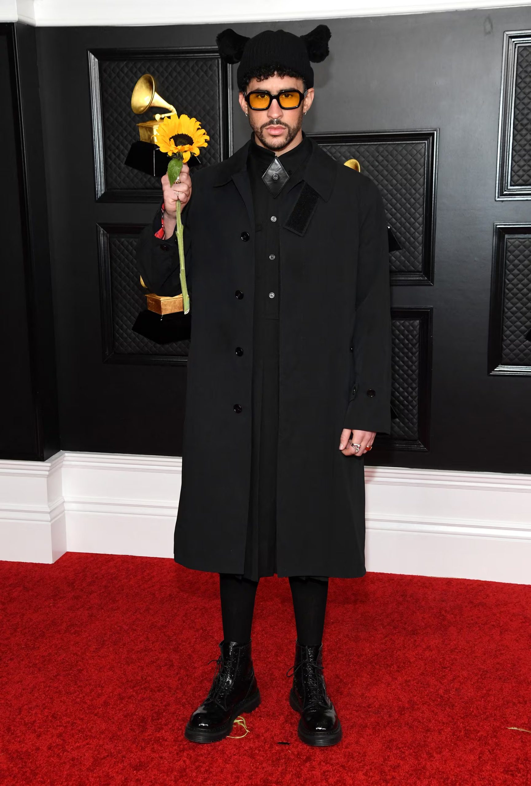 Un conjunto negro con botas de combate, gorro con orejas y un girasol en la mano resumió el estilo irreverente y simbólico de Bad Bunny (Photo by Kevin Mazur / The Recording Academy / AFP) /