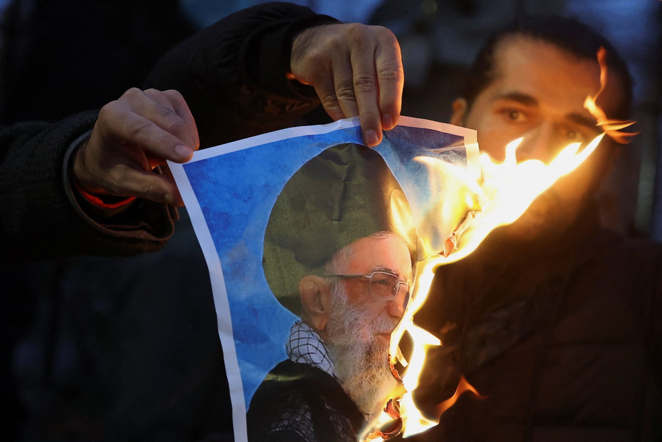 Un manifestante observa cómo arde una imagen del líder supremo iraní, Ali Jamenei, durante una protesta frente a la embajada de Irán en Londres en apoyo a las manifestaciones dentro del país (REUTERS)