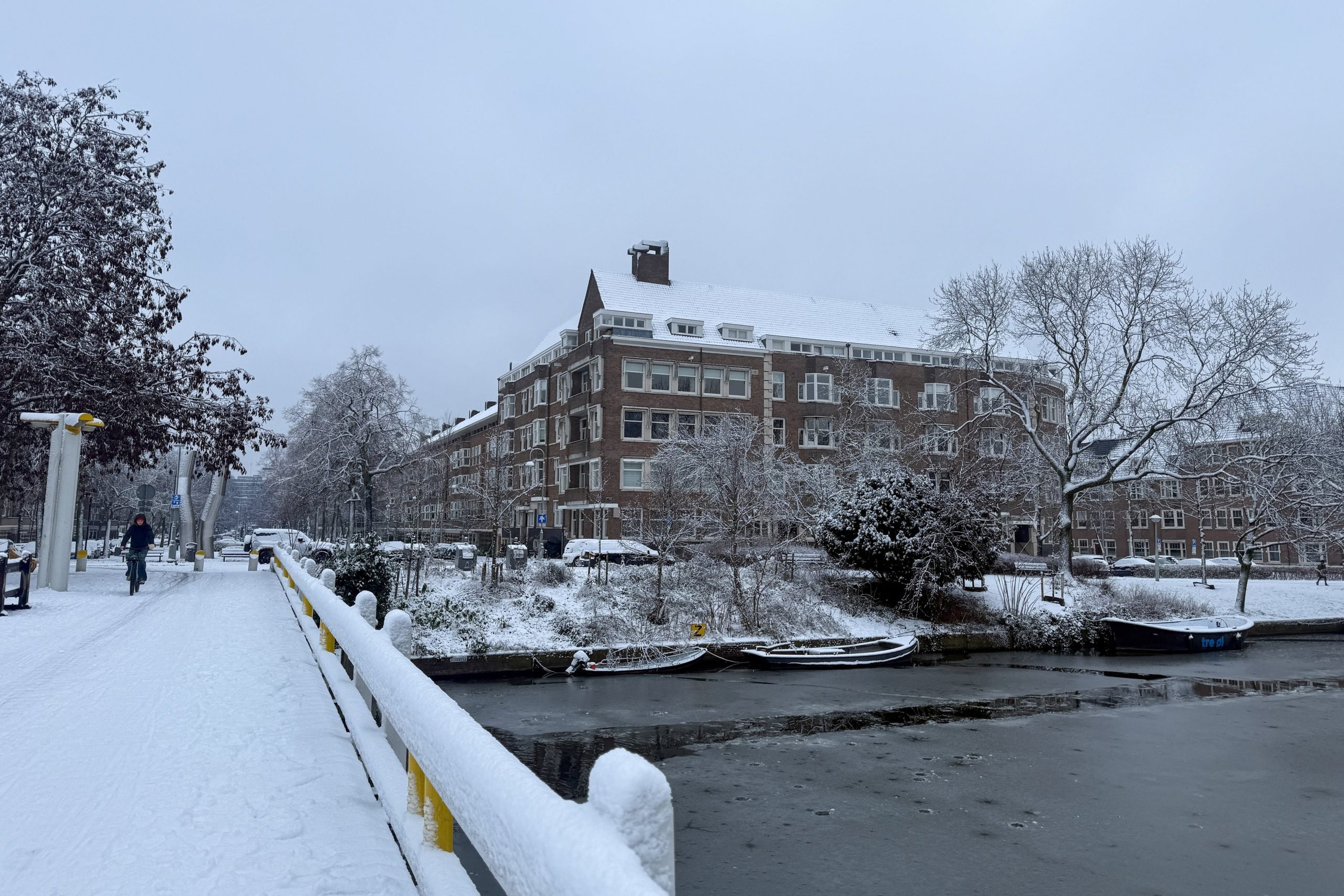 Una persona va en bicicleta en la nieve, en un puente sobre un canal fluvial cubierto de hielo en Ámsterdam, en medio de interrupciones del tráfico aéreo, ferroviario y vial causadas por las nevadas, ya que cientos de vuelos fueron cancelados y los trenes se detuvieron, en los Países Bajos, el 5 de enero de 2026. REUTERS/Charlotte Van Campenhout