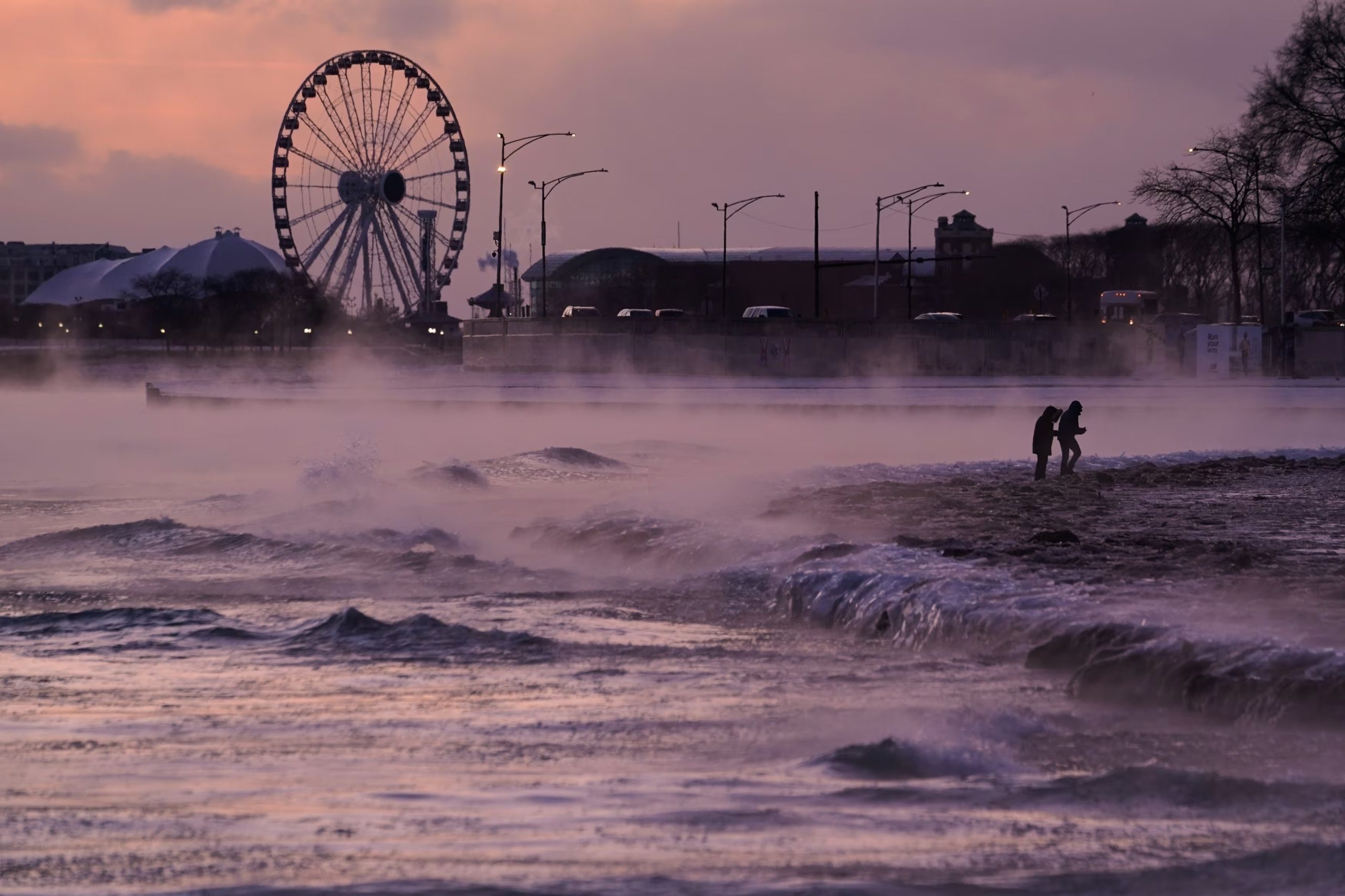Varias personas caminan por una playa cubierta de hielo en la orilla del lago Michigan, el viernes 23 de enero de 2026, en Chicago (Associated Press/Kiichiro Sato)