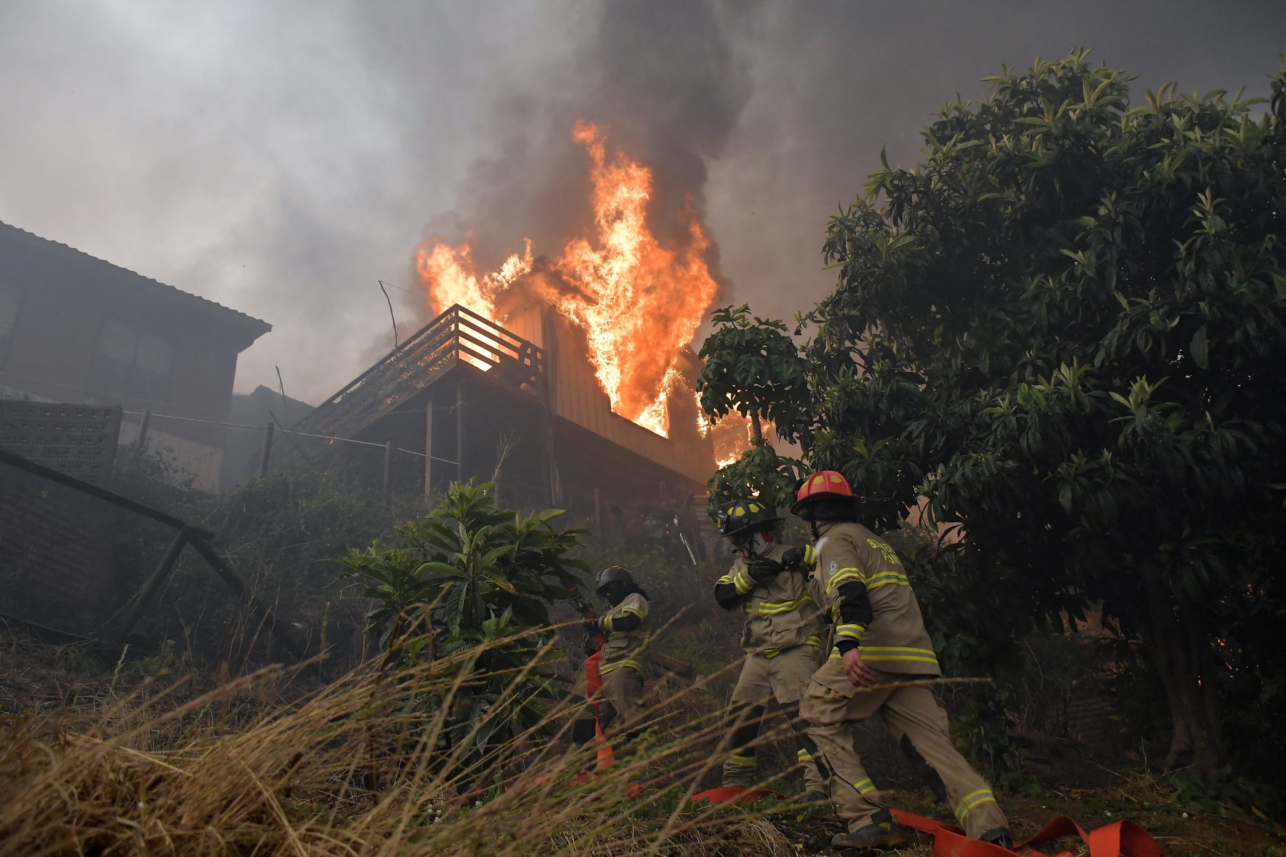 Un equipo de bomberos trabaja para apagar una vivienda en llamas durante la emergencia por incendios forestales en Concepción (GUILLERMO SALGADO / AFP)