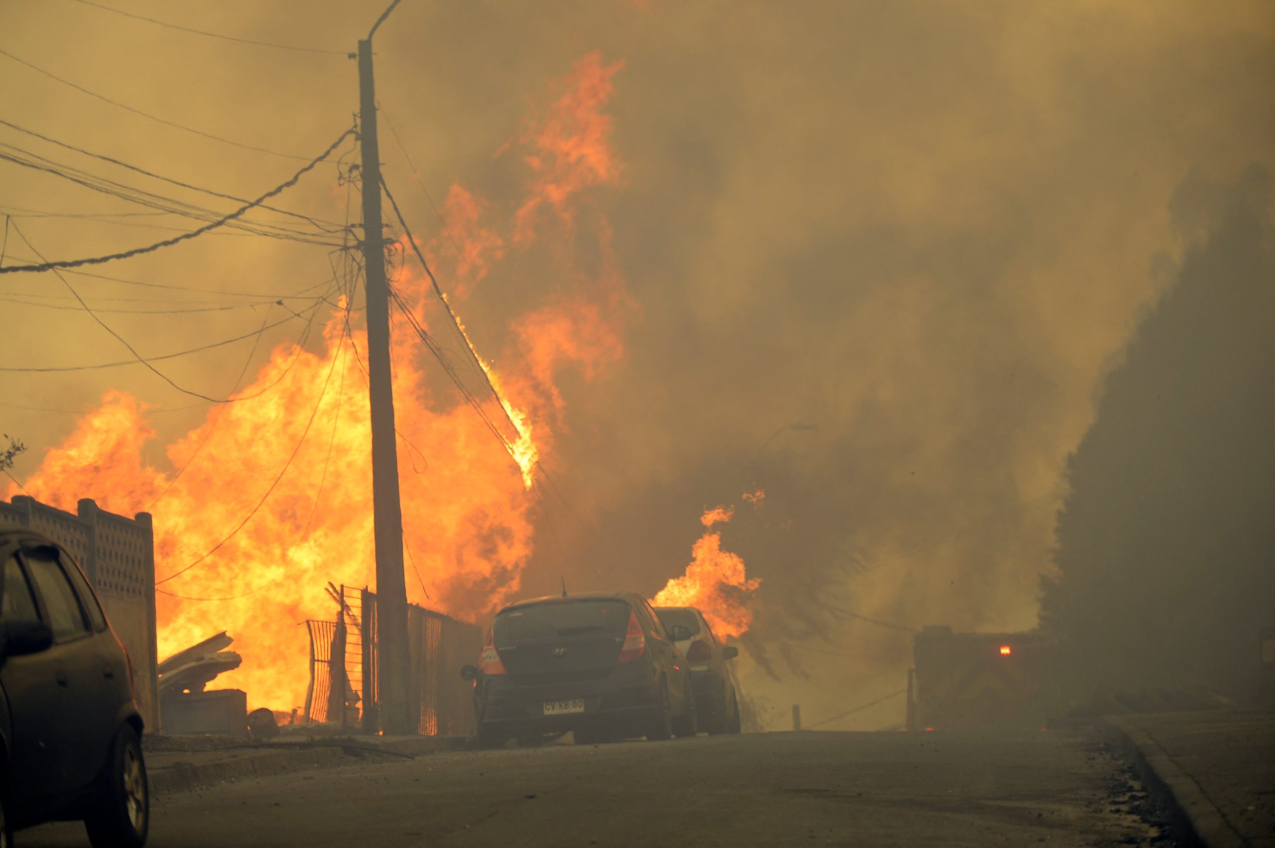 Humo y llamas se elevan desde una vivienda y un vehículo durante los incendios forestales en el sur de Chile (GUILLERMO SALGADO / AFP)