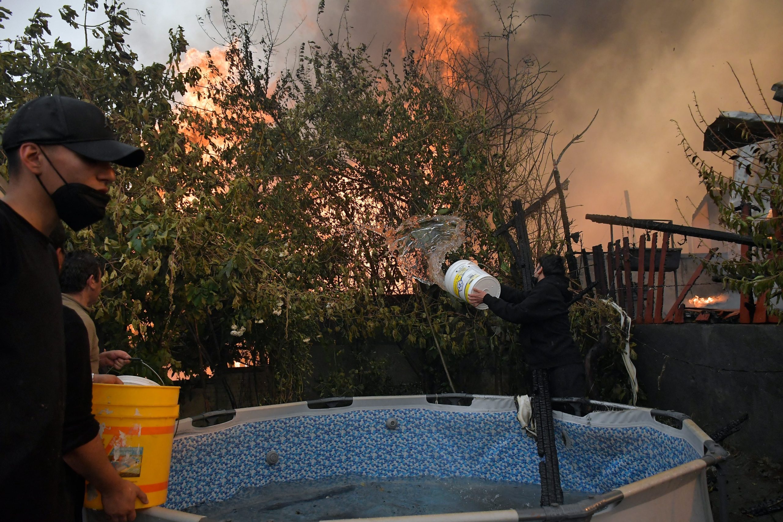 Un grupo de personas observa el avance del incendio desde un cerro en Penco (GUILLERMO SALGADO / AFP)