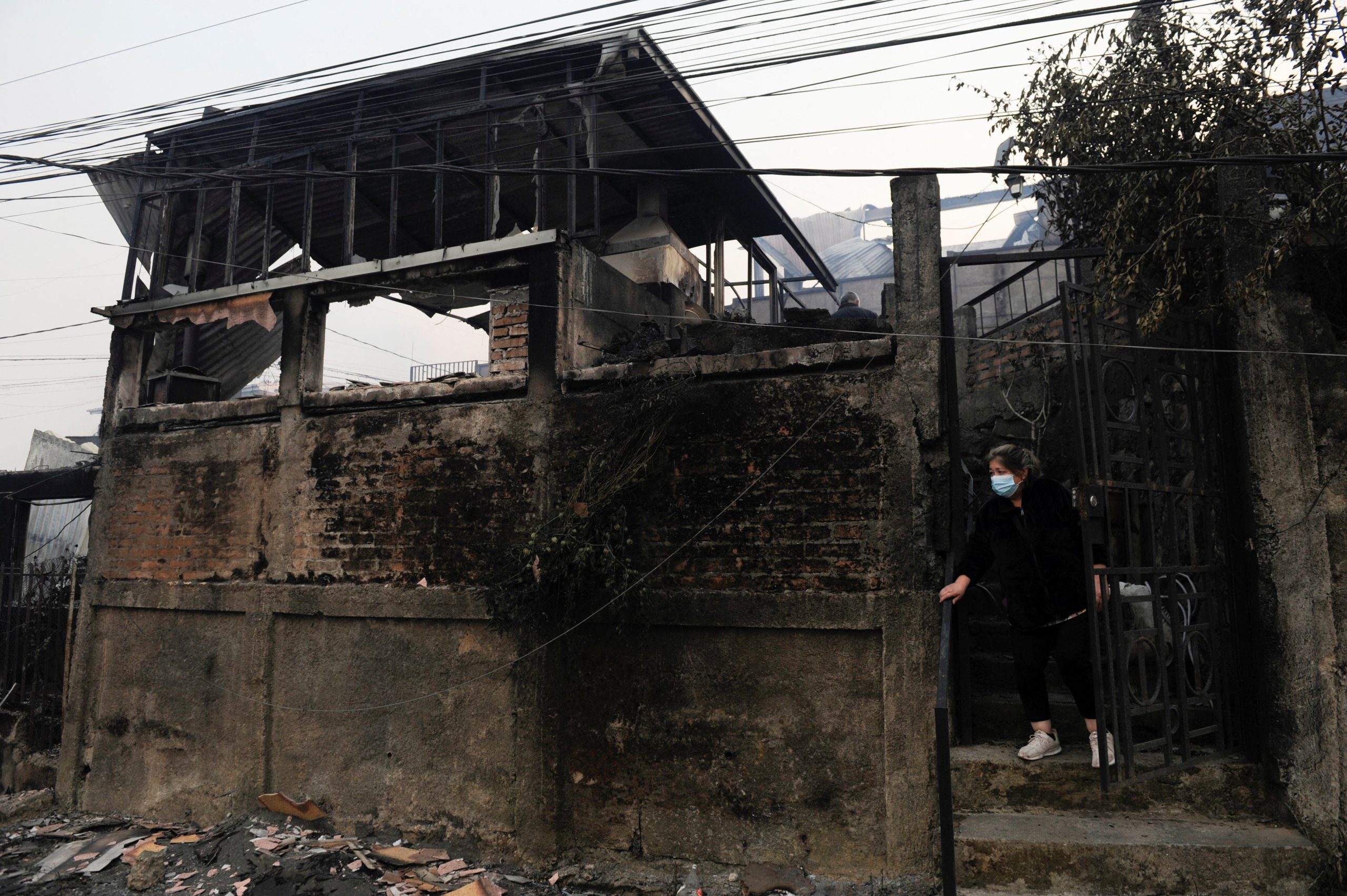 Una persona sale de un edificio dañado tras los incendios forestales que obligaron a evacuar varias zonas en Lirquén (REUTERS/Jose Luis Saavedra)