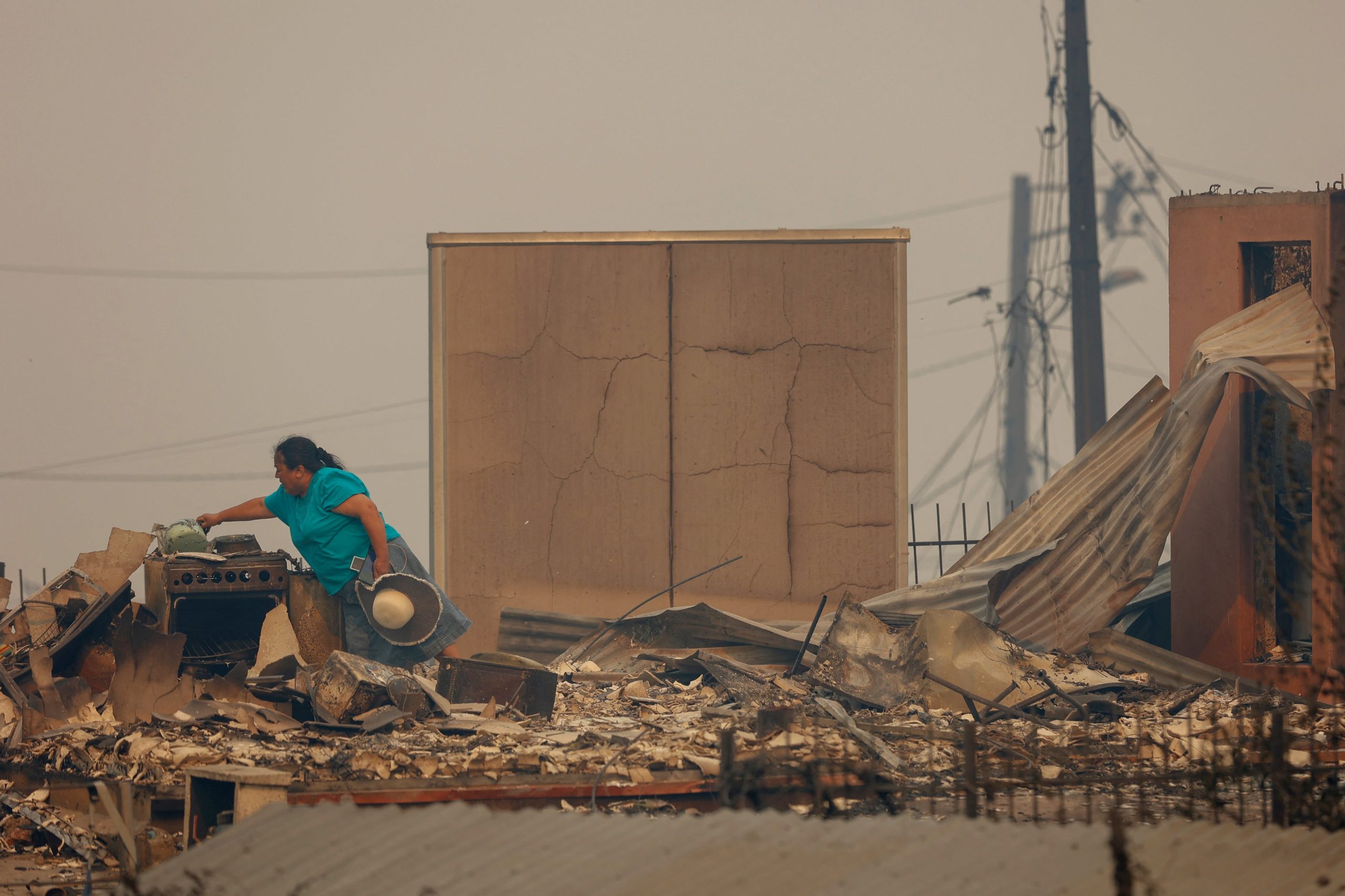 Una mujer recupera objetos entre las ruinas de su casa destruida por incendios forestales en Concepción (RAUL BRAVO / AFP)