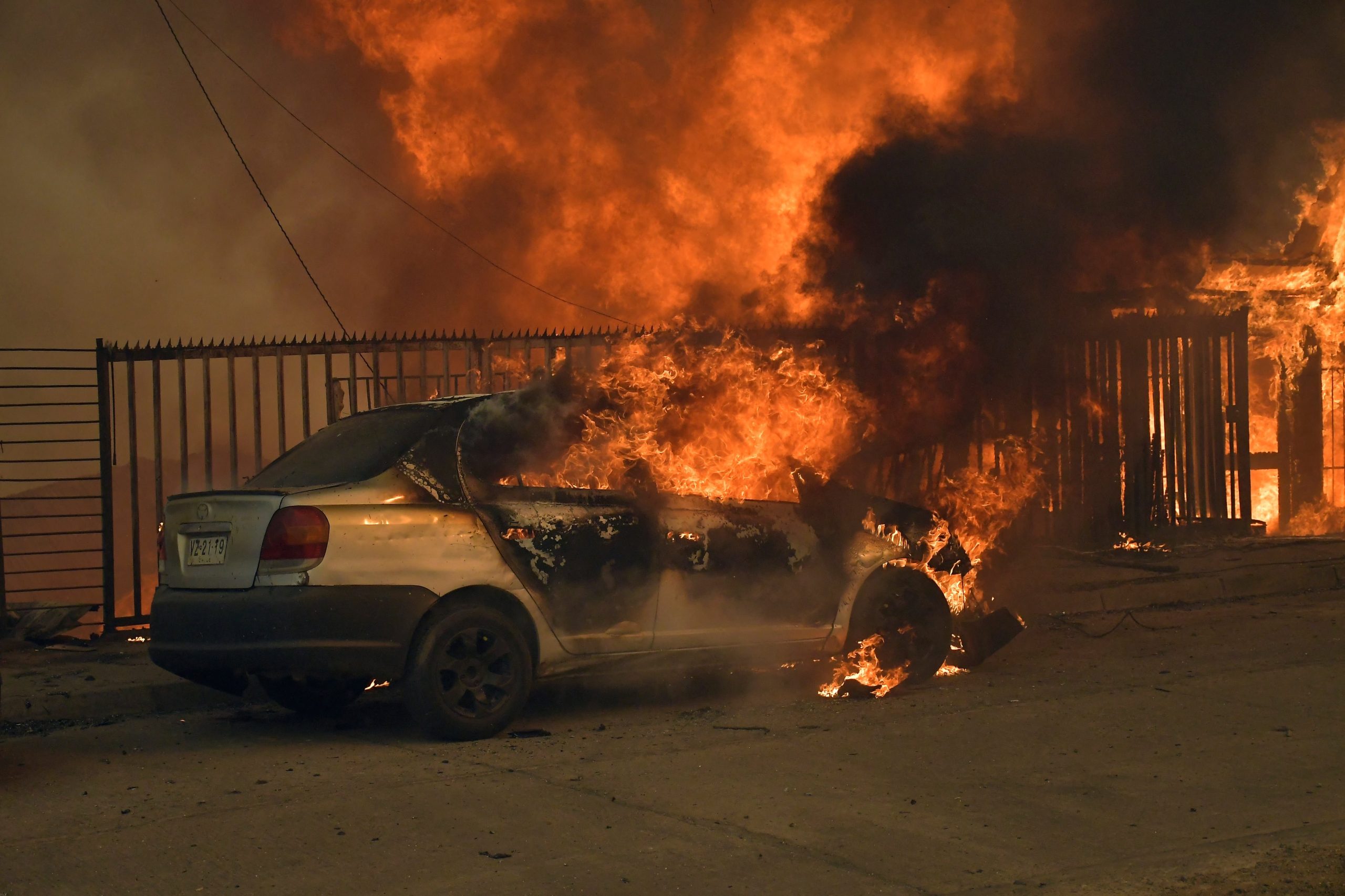 Un vehículo y una vivienda envueltos en llamas durante los incendios forestales en Concepción (GUILLERMO SALGADO / AFP)