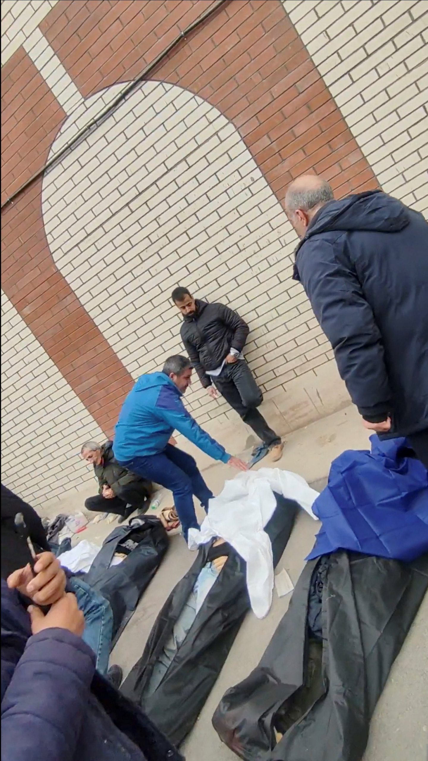 Un hombre cubre uno de los cuerpos (Social Media/via REUTERS)