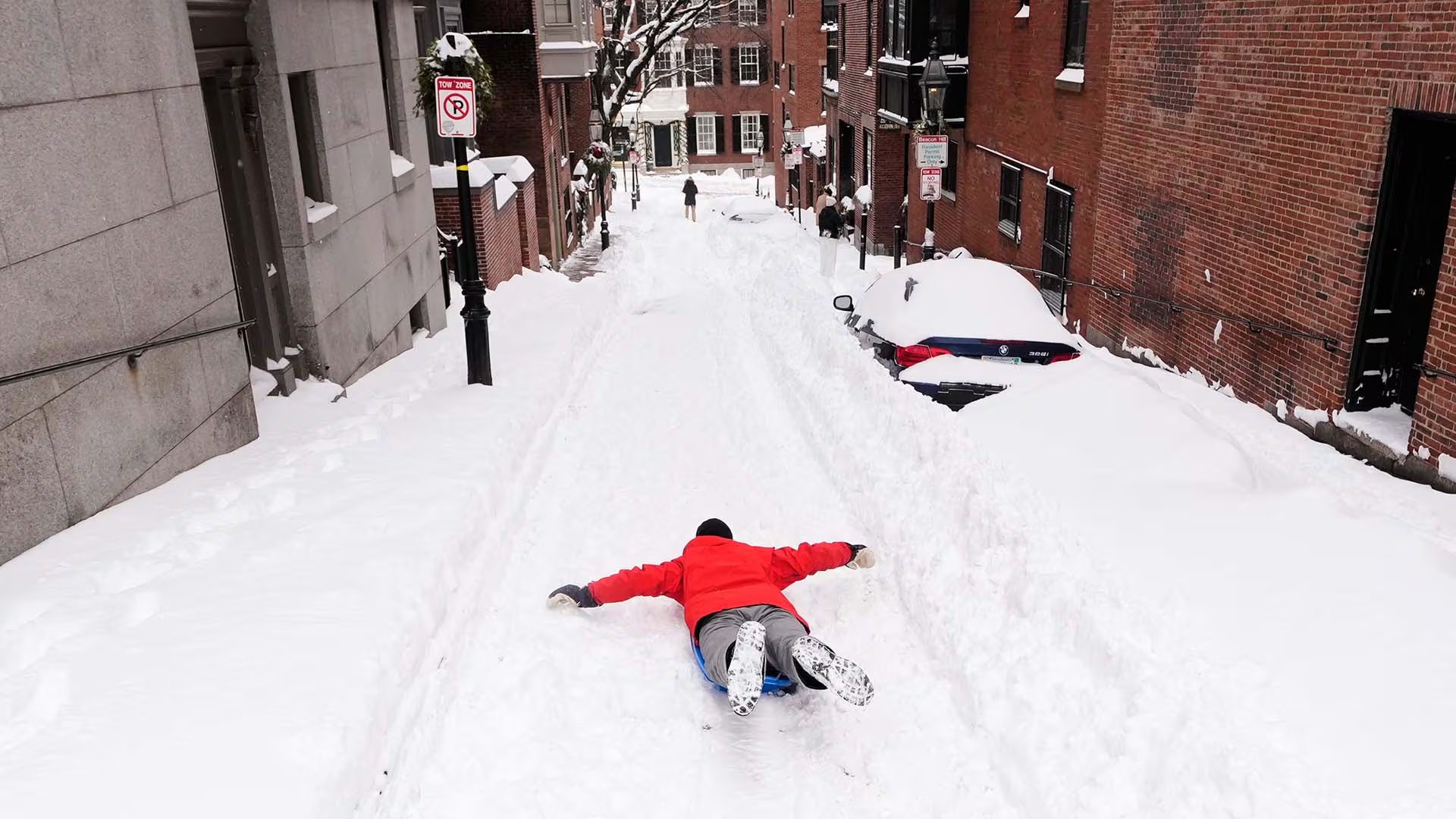 Ian Flood se desliza en trineo por una calle de su barrio de Beacon Hill tras una tormenta invernal que dejó más de 30 centímetros de nieve en la región, el lunes 26 de enero de 2026, en Boston (AP Foto/Charles Krupa)