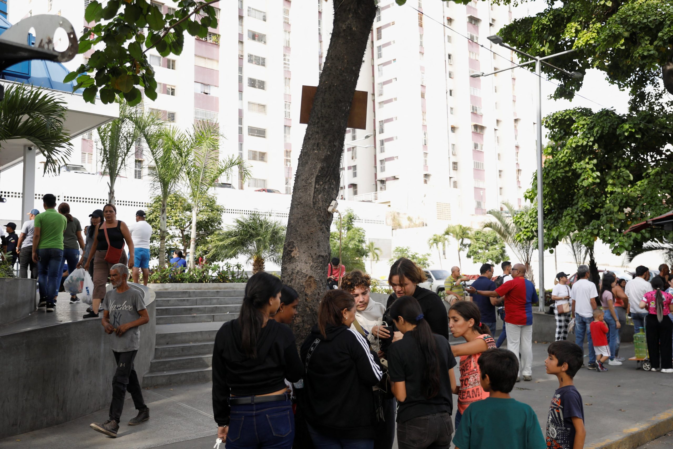 Personas cargan sus teléfonos con un cable de extensión conectado a una lámpara de calle tras la operación donde fueron capturados el presidente Nicolás Maduro y su esposa, Cilia Flores