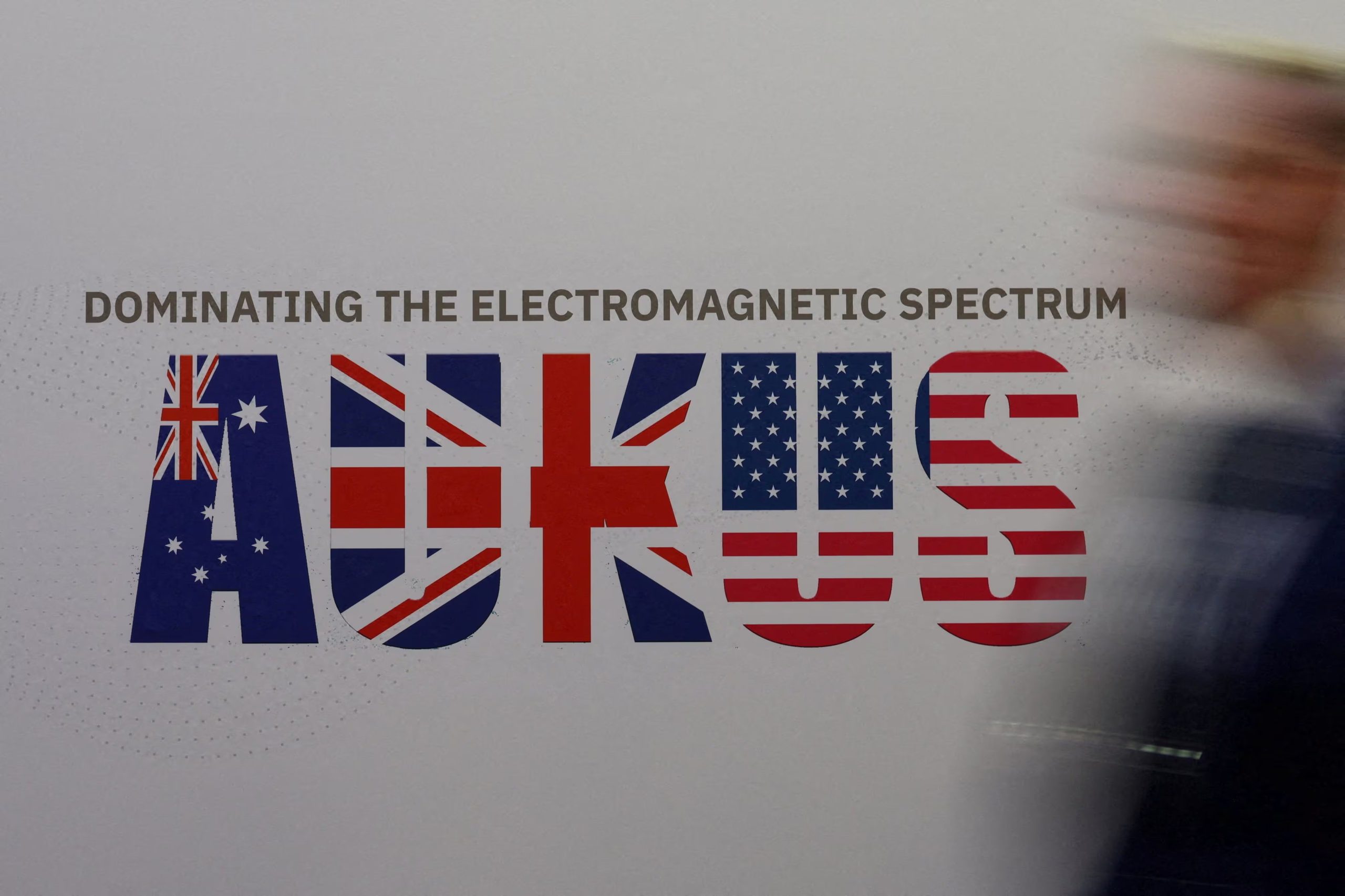 Un hombre pasa junto a un cartel de AUKUS el primer día de la Exposición Marítima Internacional Indo-Pacífico en Sídney, Australia, el 4 de noviembre de 2025 (REUTERS/Hollie Adams/Archivo)