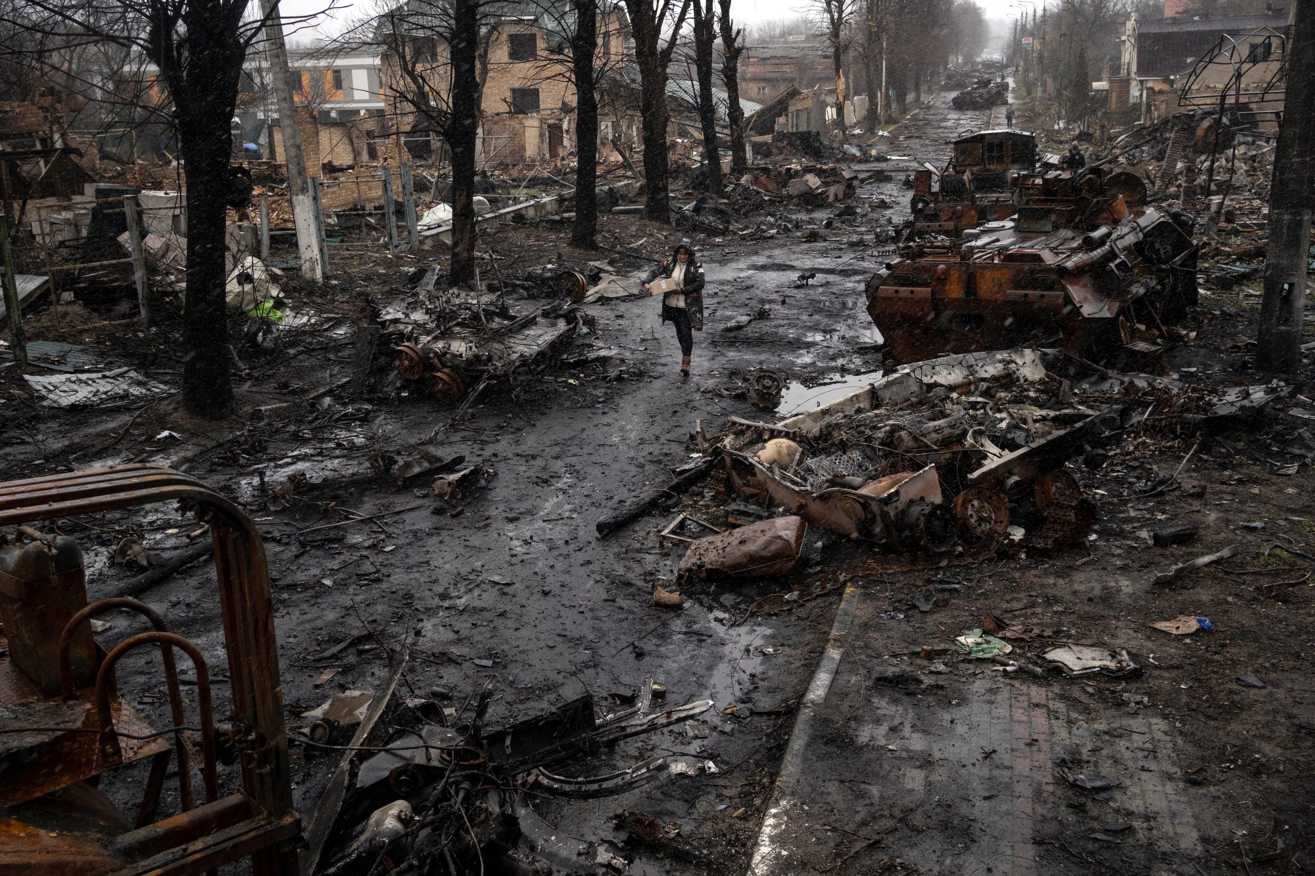 Una mujer transita por una calle cubierta de escombros donde se encuentran vehículos militares rusos destruidos en Bucha, en las afueras de Kiev, Ucrania, el domingo 3 de abril de 2022 (AP/Rodrigo Abd, Archivo)