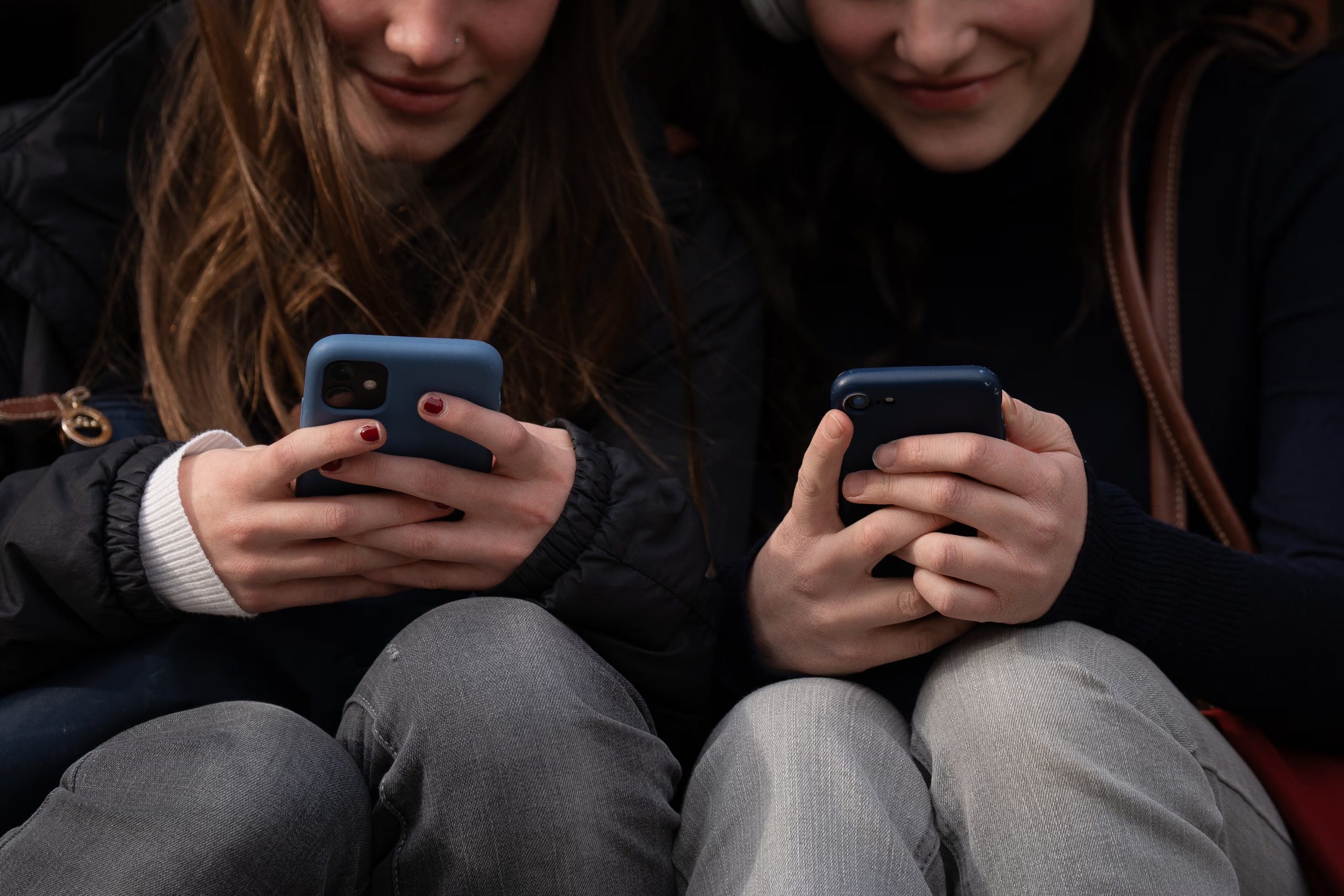 Dos personas usan el teléfono móvil, a 1 de febrero de 2024, en Barcelona. (David Zorrakino / Europa Press)