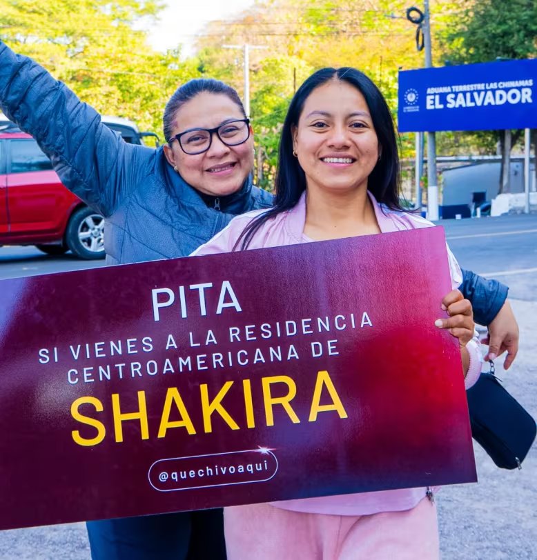 Dos mujeres guatemaltecas posan sonrientes en el paso fronterizo Las Chinamas, en El Salvador, sosteniendo un cartel alusivo a la residencia centroamericana de Shakira (Foto cortesía de Que chivo aquí).