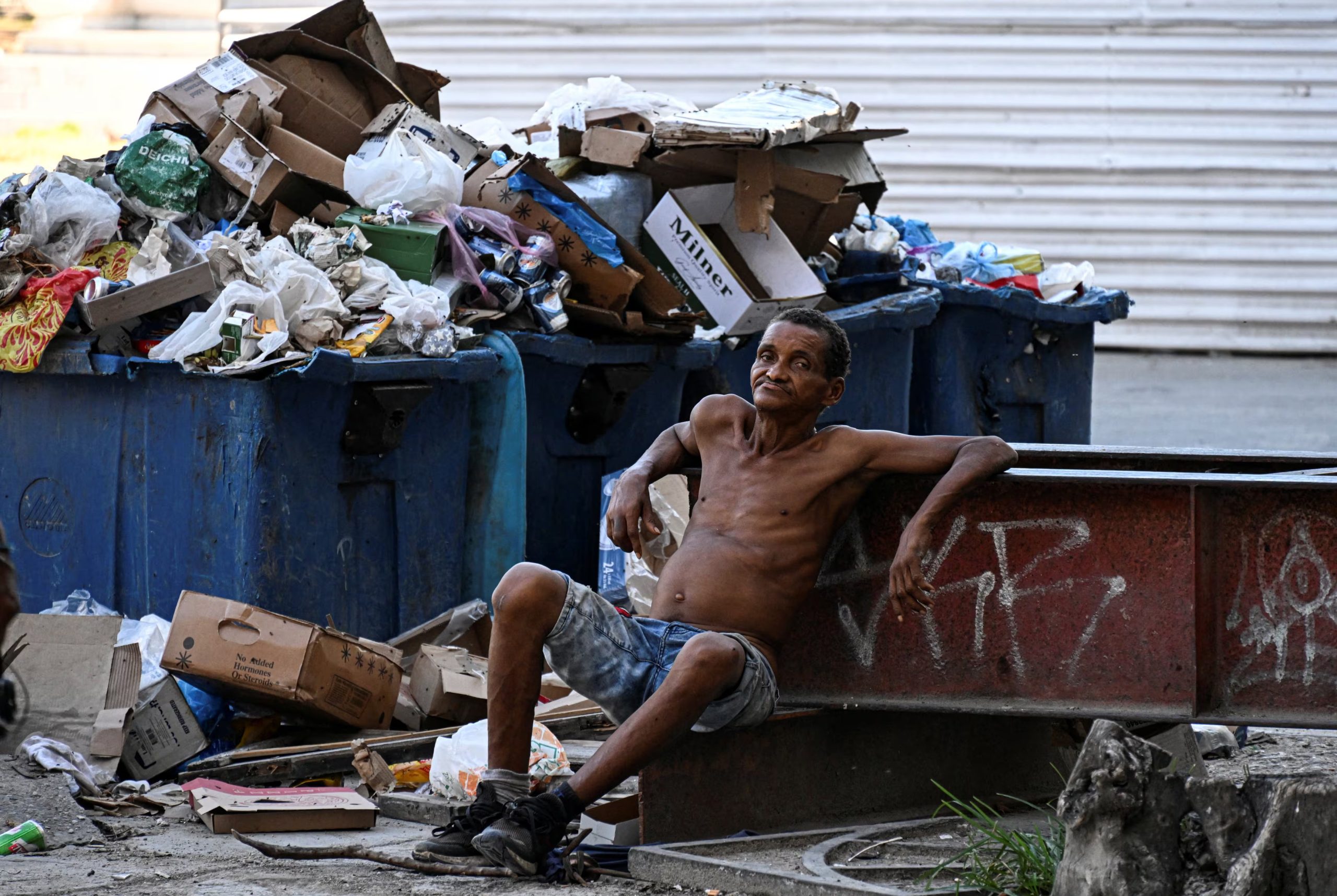 Un hombre descansa junto a botes de basura (Yamil LAGE/AFP)