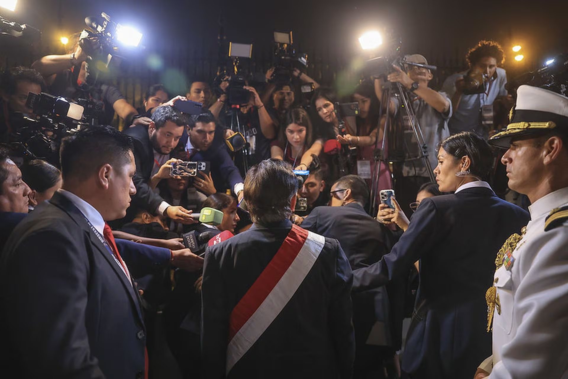 José María Balcázar, vistiendo la banda presidencial, es recibido por una multitud de periodistas y seguridad al llegar a Palacio de Gobierno la noche del 18 de febrero de 2023, tras jurar como presidente del Perú. (Presidencia del Perú)