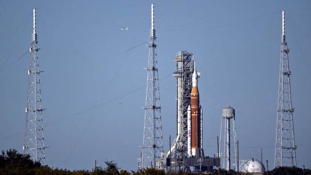 El cohete del programa Artemis II se alza imponente en la plataforma de lanzamiento, con la estructura de la torre de servicio y el icónico Vehicle Assembly Building de fondo, listo para misiones lunares. (Reuters)