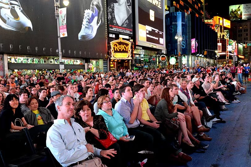Multitudes se congregan en Times Square, epicentro del distrito teatral, en una noche de alta actividad cultural.