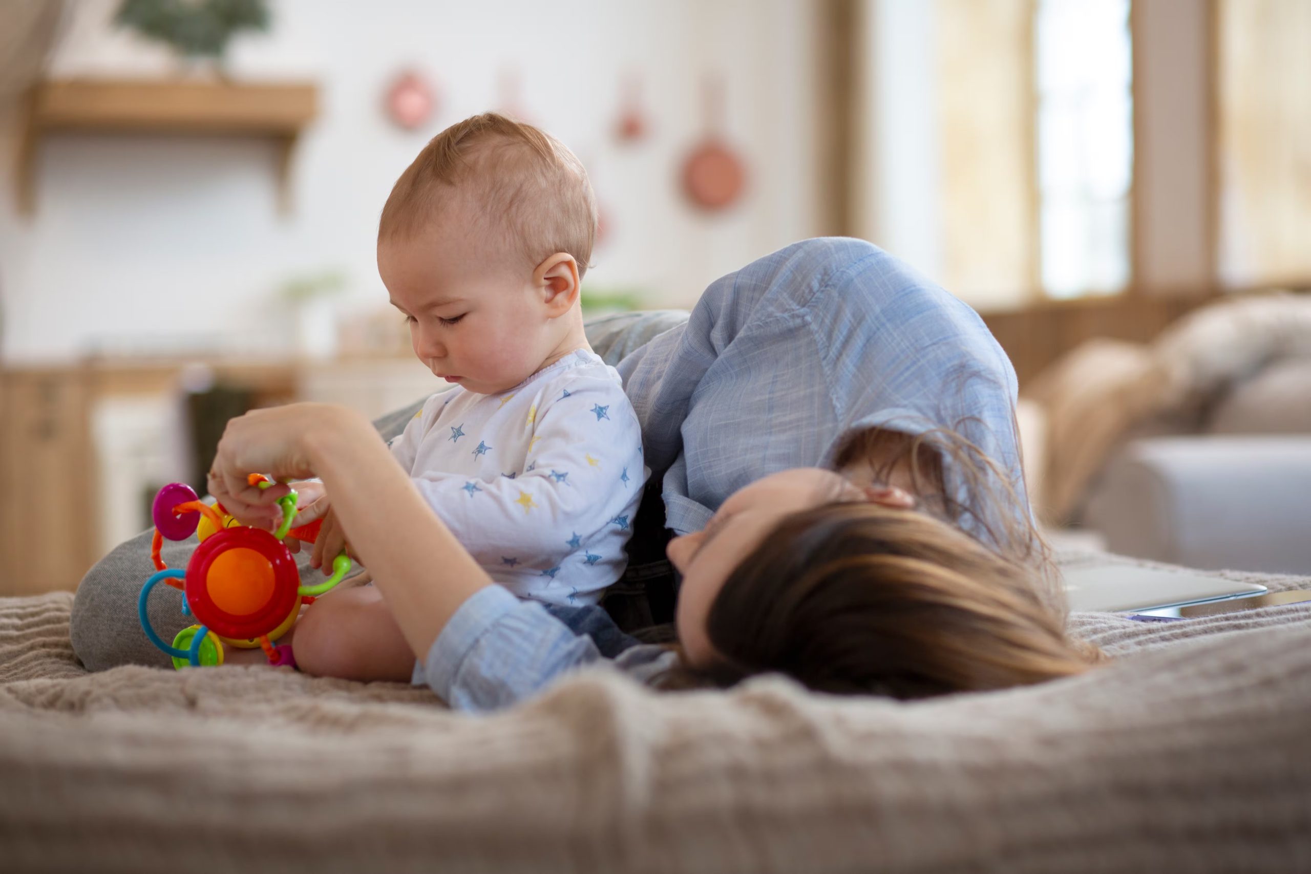 Una madre jugando en la cama con su bebé (Freepik)
