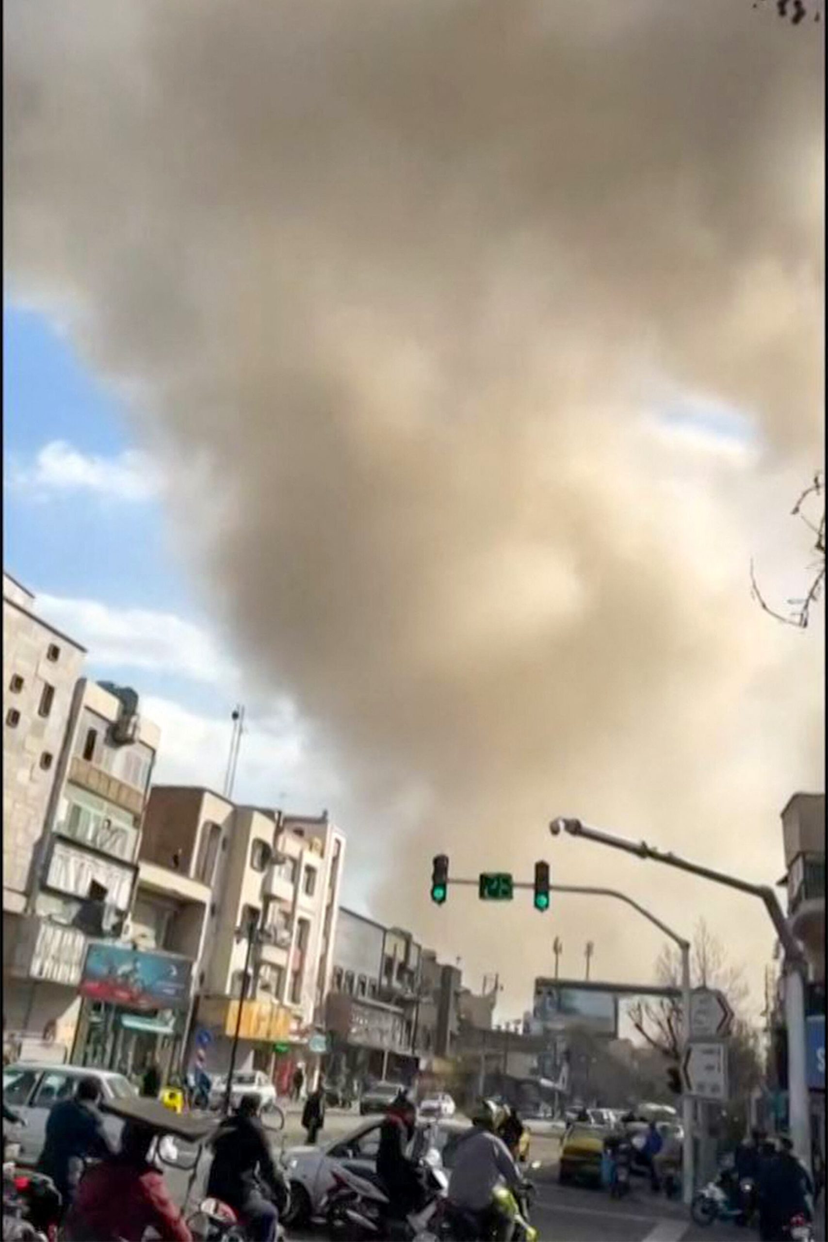 Esta imagen tomada de un video de UGC publicado en redes sociales el 28 de febrero de 2026 y verificada por equipos de AFPTV en París muestra el tránsito circulando mientras una columna de humo se eleva tras una explosión reportada en Teherán. (AFP - Fuente: UGC)