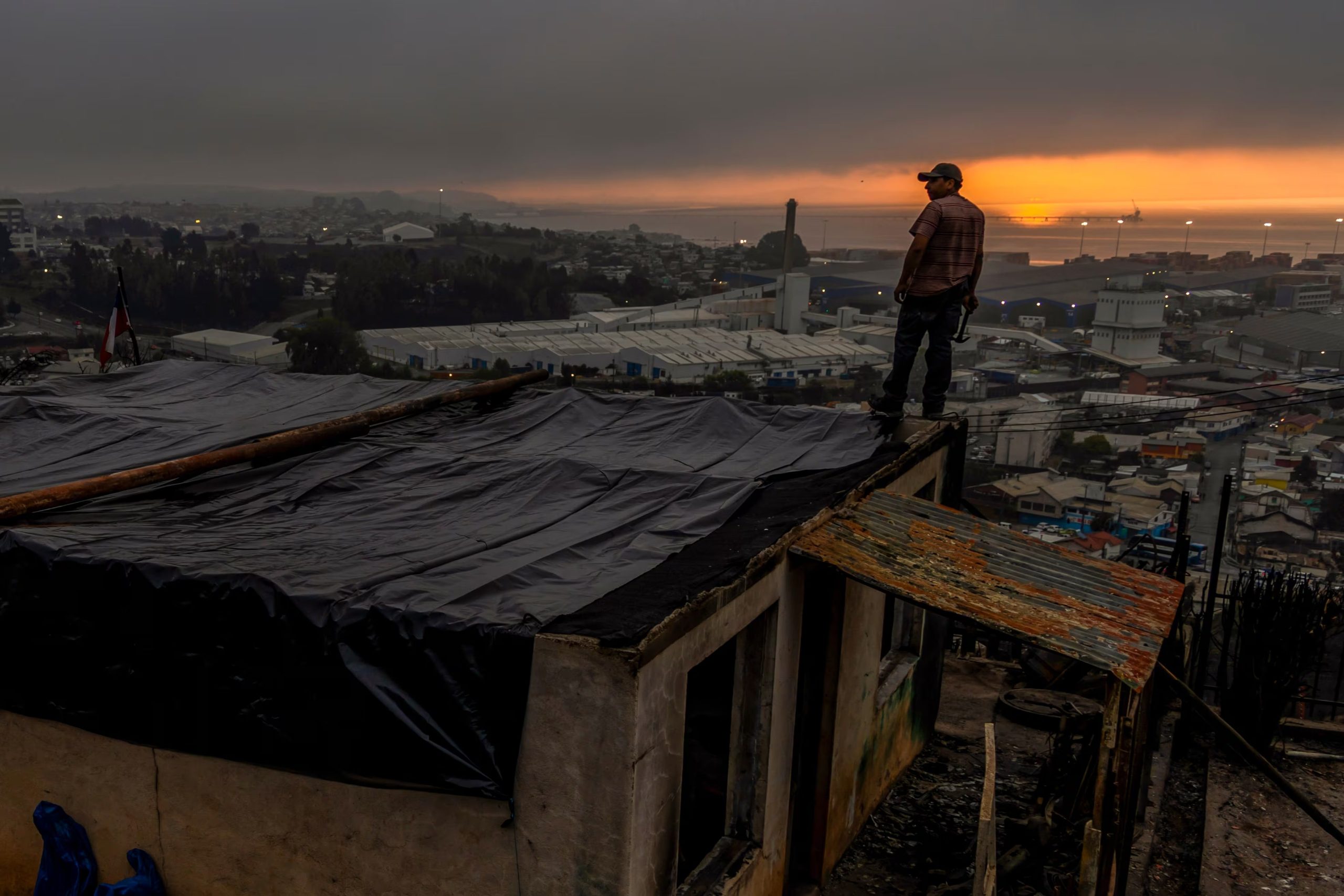 Jonathan Escalona, sobre el tejado de su casa, dañada por los incendios en Lirquen, Chile, el 20 de enero de 2026. (AP Foto/Javier Torres)