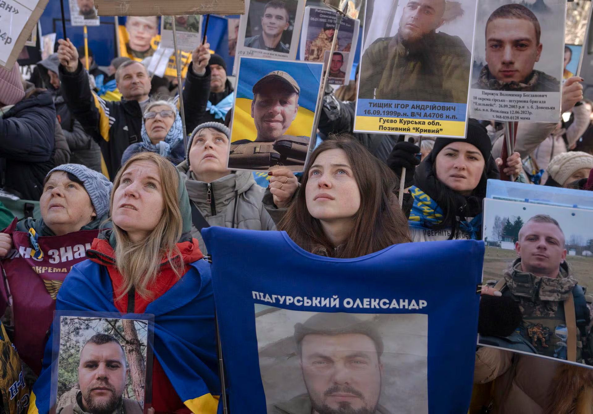 Ciudadanos ucranianos se congregan sosteniendo retratos de soldados, muchos de ellos mirando hacia arriba en un acto de memoria y búsqueda de información sobre sus seres queridos en medio del conflicto. (ANDREW KRAVCHENKOEFE)