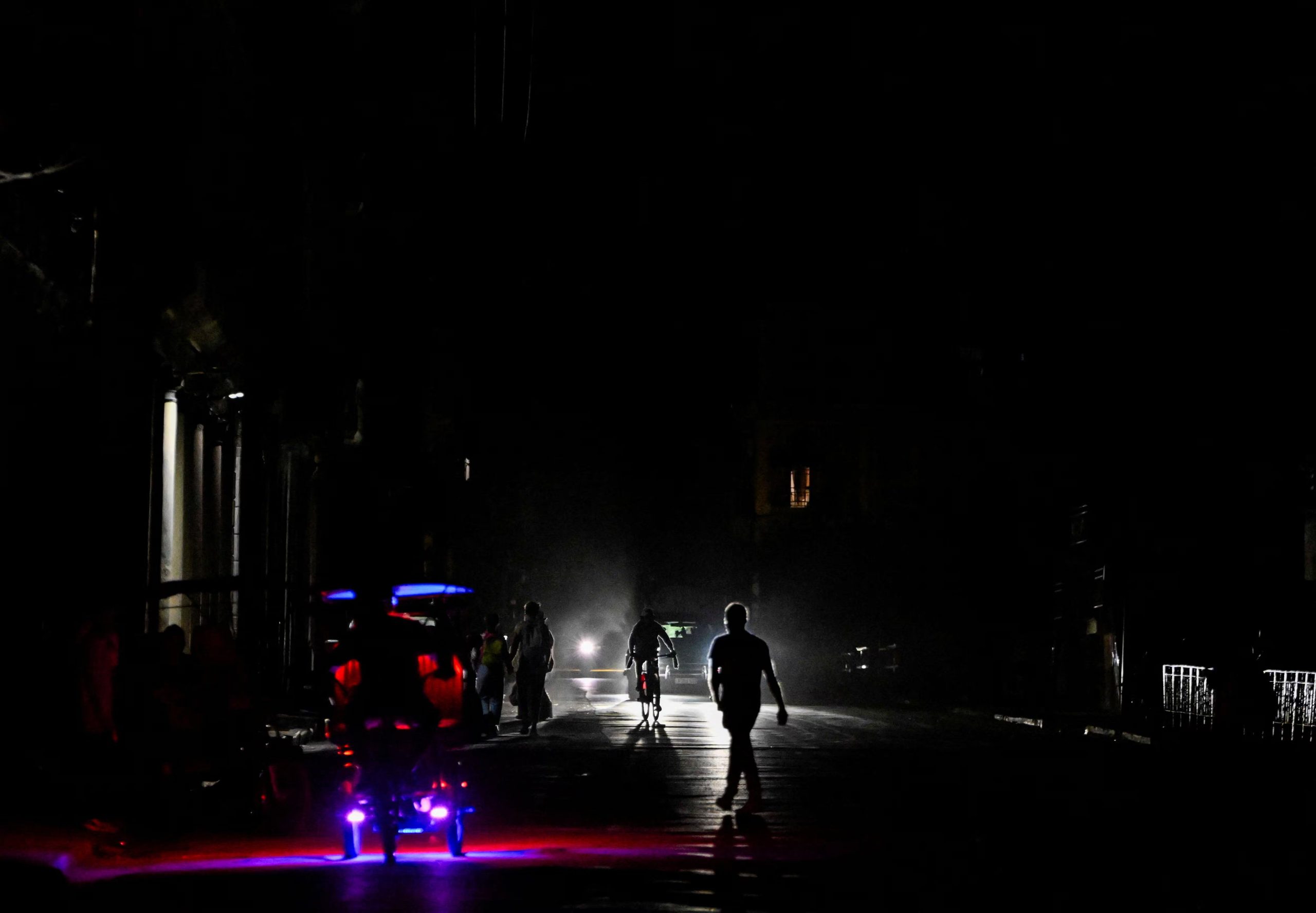 Personas caminan y conducen en una calle tras el colapso de la red eléctrica nacional de Cuba (REUTERS/Norlys Perez)