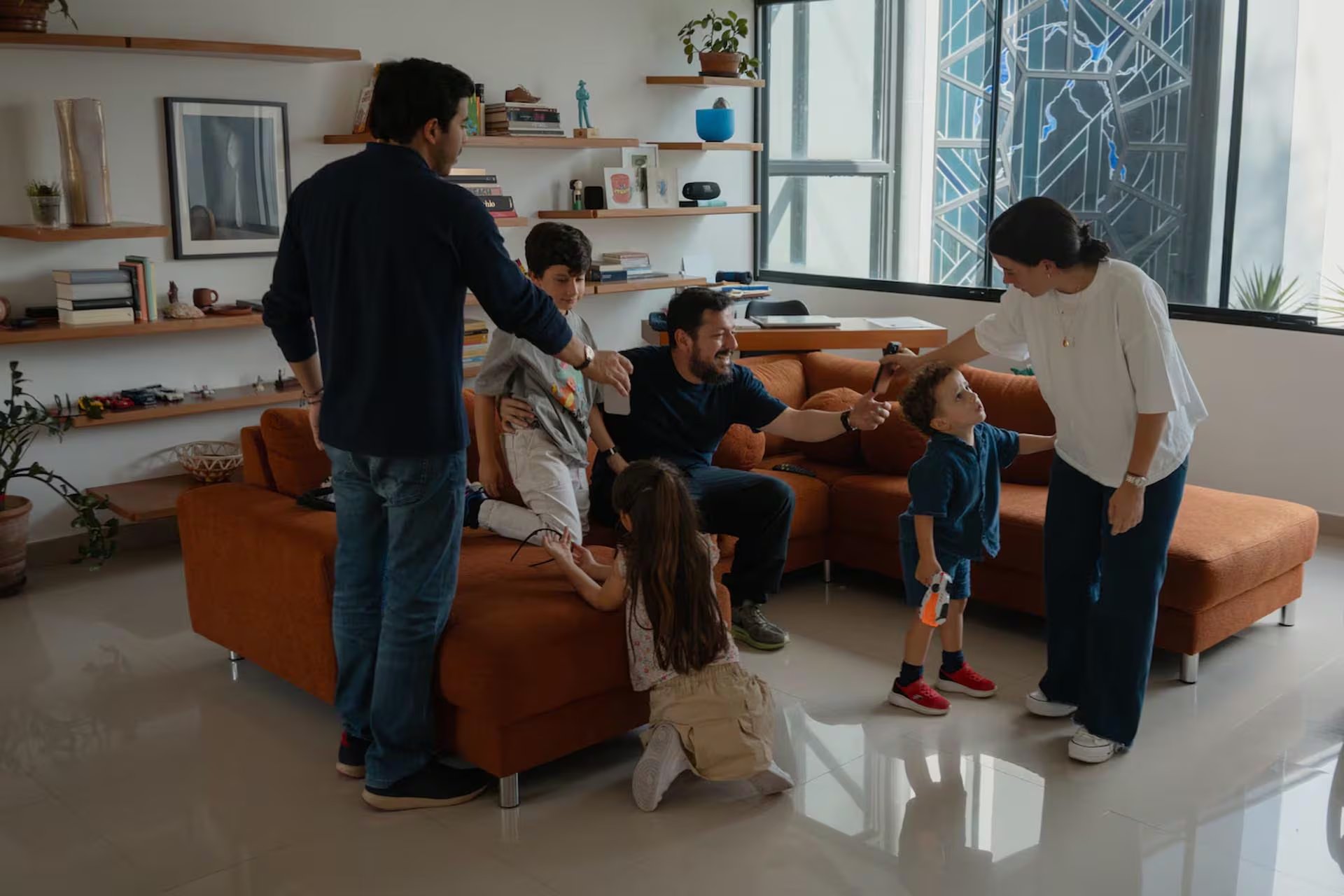 Luis se sienta en la sala con sus hijos Mateo y Andrés y su esposa, Vanessa, junto a otros miembros de la familia, tras su regreso (Andrea Hernández Briceño/Para The Washington Post)