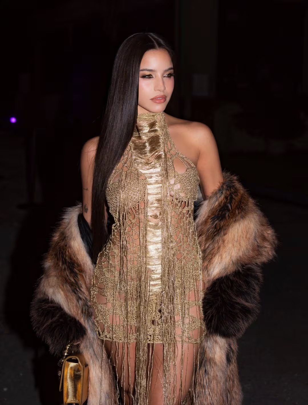 El vestido dorado de malla metálica y el abrigo de pelo sintético convirtieron a Emilia Mernes en una de las figuras más llamativas y originales de la jornada (Instagram: @Emiliamernes)