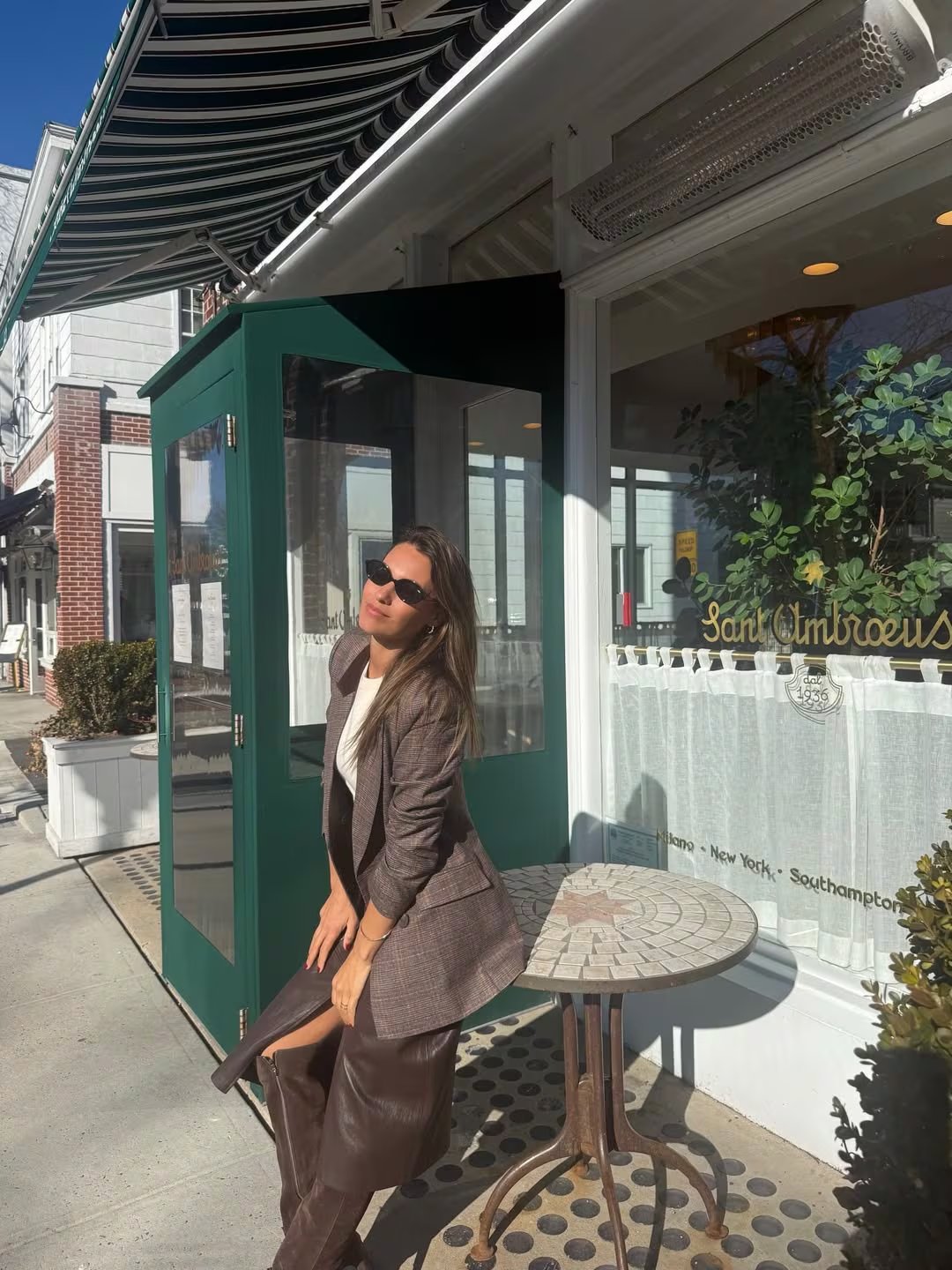 Pampita posa elegantemente con un atuendo otoñal de blazer a cuadros y falda de cuero en una calle soleada de Nueva York