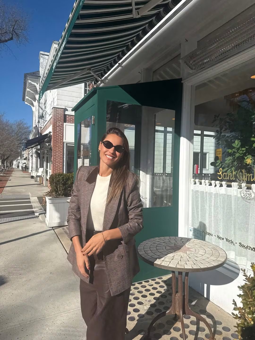 Pampita posa sonriente con un elegante look de otoño frente a un café en Nueva York, mostrando su impecable sentido de la moda