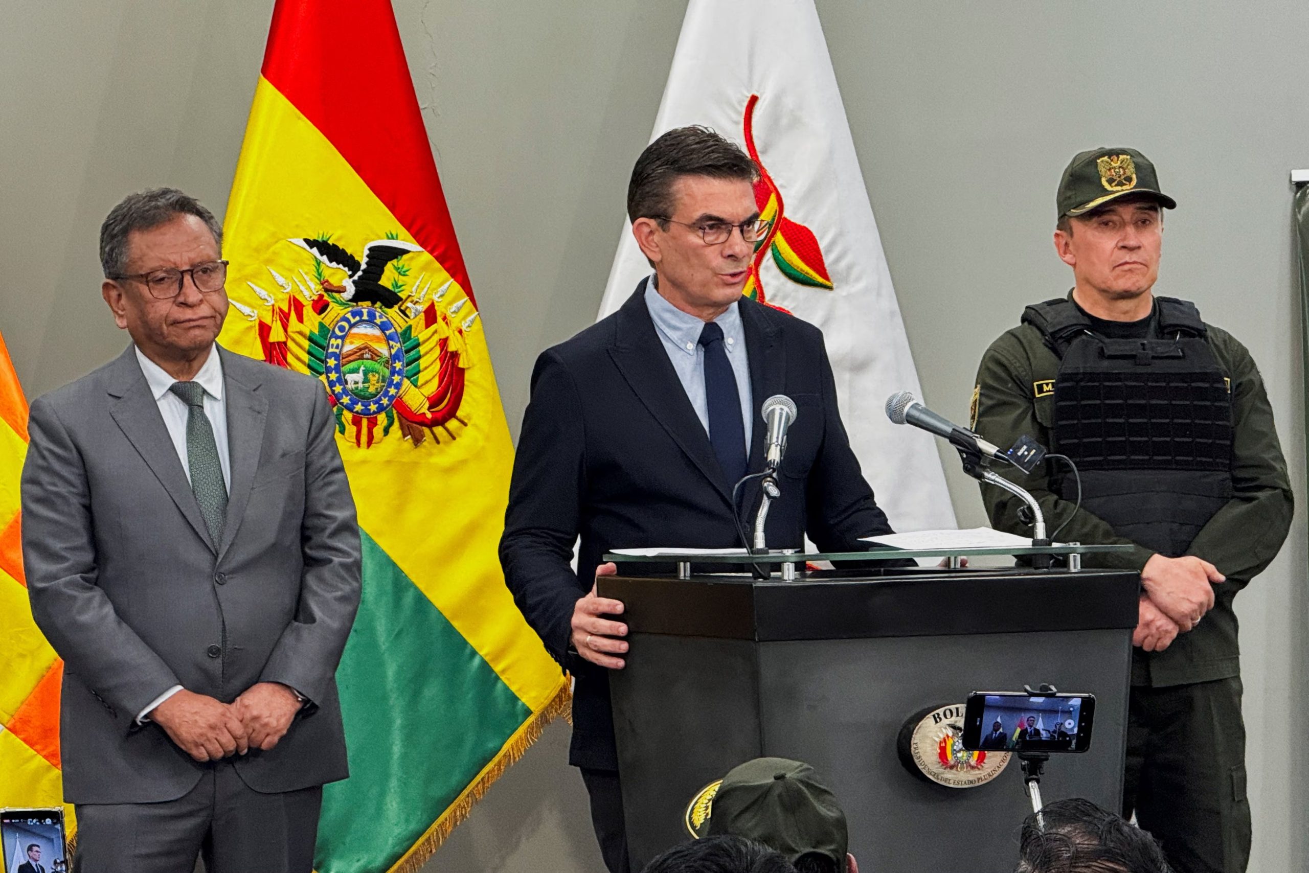 El presidente de Bolivia, Rodrigo Paz, flanqueado por el ministro del Interior, Marco Oviedo, y el jefe de la Policía, Mirko Sokol, habla durante una conferencia de prensa tras una operación para arrestar al presunto narcotraficante uruguayo Sebastián Marset, acusado de liderar el Primer Cártel Uruguayo y buscado por la Interpol por delitos de crimen organizado y lavado de dinero, en La Paz, Bolivia, el 13 de marzo de 2026. Fotografía tomada con un teléfono móvil. REUTERS/Sergio Limachi
