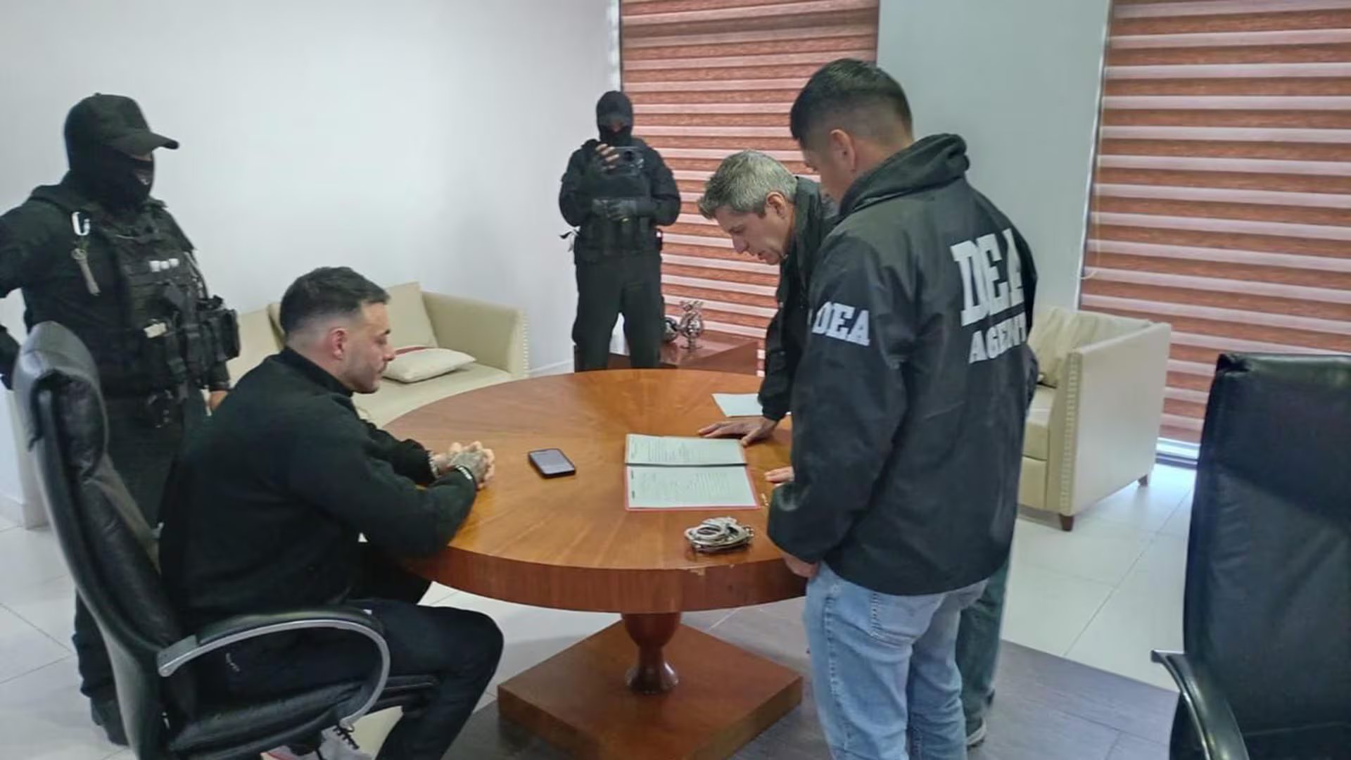 Sebastián Marset es capturado en Bolivia el 13 de marzo de 2026, sentado en una mesa con agentes de seguridad que revisan documentos durante el operativo.