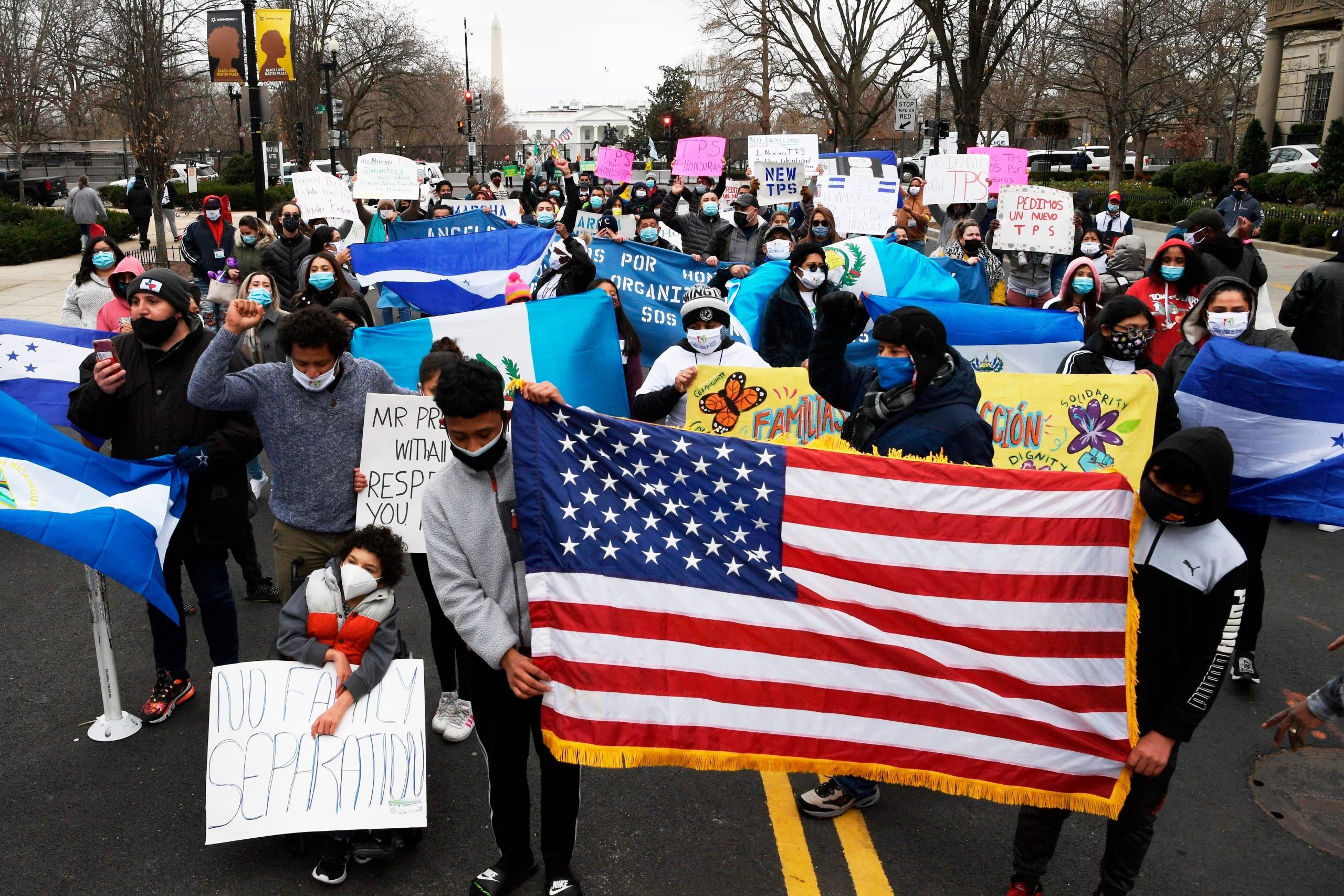 Decenas de hondureños sostienen pancartas y banderas estadounidenses mientras marchan dirección a la Casa Blanca hoy, en Washington (EE.UU.). EFE/Lenin Nolly
