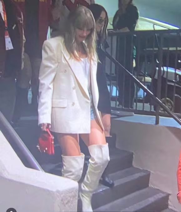 Las botas altas blancas y el blazer oversize en tono a juego crean un conjunto urbano y deportivo para Taylor Swift en el Super Bowl LIX