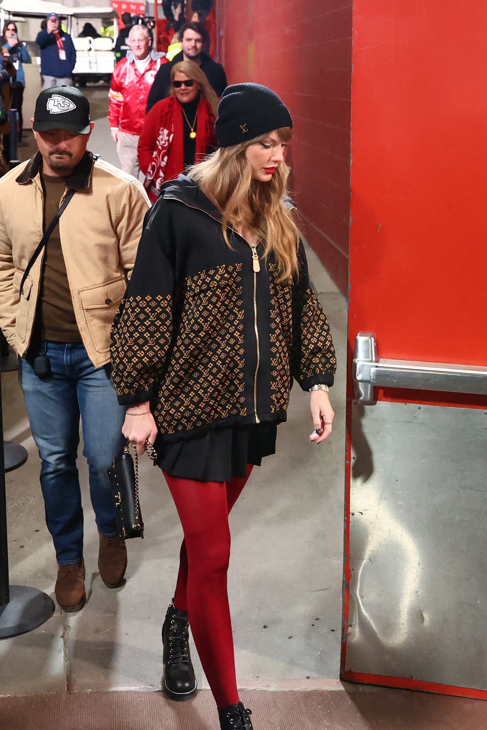 El abrigo con monograma marrón y negro de Louis Vuitton junto a medias rojas opacas marca el estilo urbano de Taylor Swift en un partido en Los Ángeles (REUTERS)