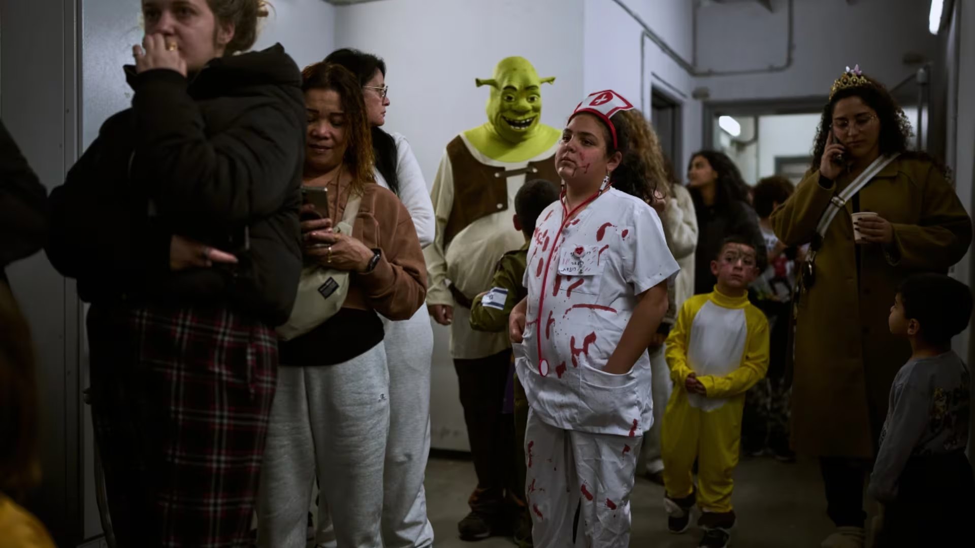 Varias personas, algunas vestidas con disfraces de la festividad judía de Purim, se congregan en una estación de metro subterránea utilizada como refugio contra posibles ataques con misiles iraníes en Ramat Gan, Israel, el lunes 2 de marzo de 2026 (AP/Oded Balilty)