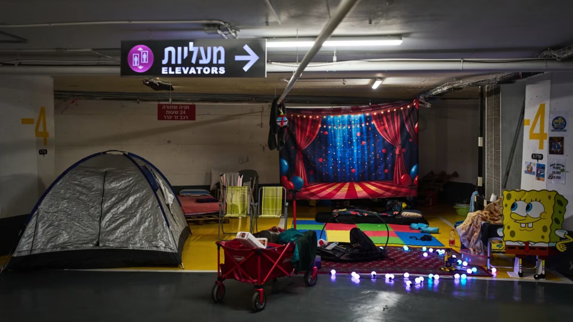 Tiendas de campaña, colchones y juguetes infantiles se encuentran esparcidos por un estacionamiento subterráneo donde la gente pasa la noche como medida de precaución ante posibles ataques con misiles iraníes en Tel Aviv, Israel, el jueves 12 de marzo de 2026 (AP/Oded Balilty)