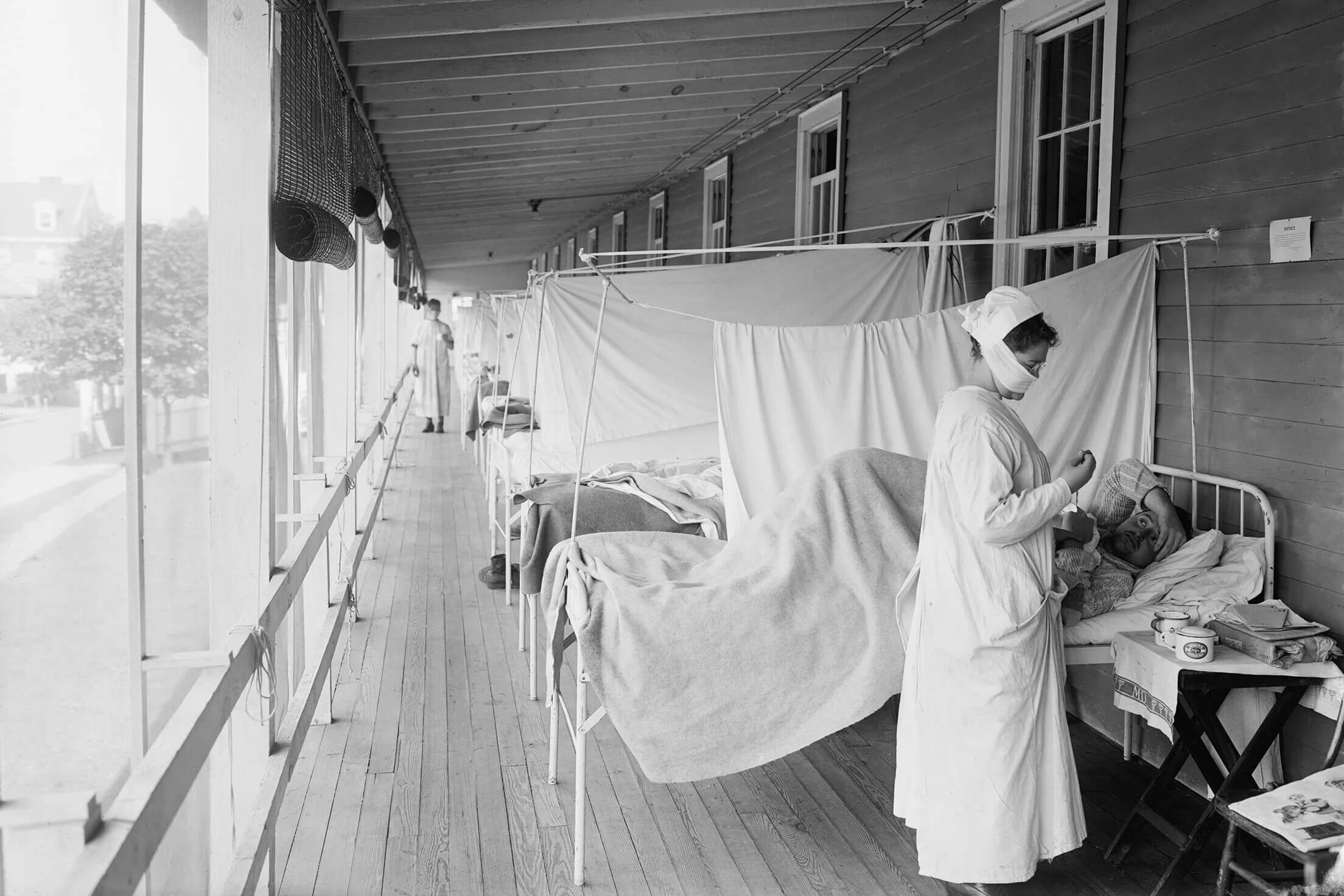 Una enfermera atiende a un paciente con gripe española en el hospital militar Walter Reed, Washington D.C., 1918. Las salas improvisadas y el uso de mascarillas reflejan las medidas adoptadas ante el colapso sanitario