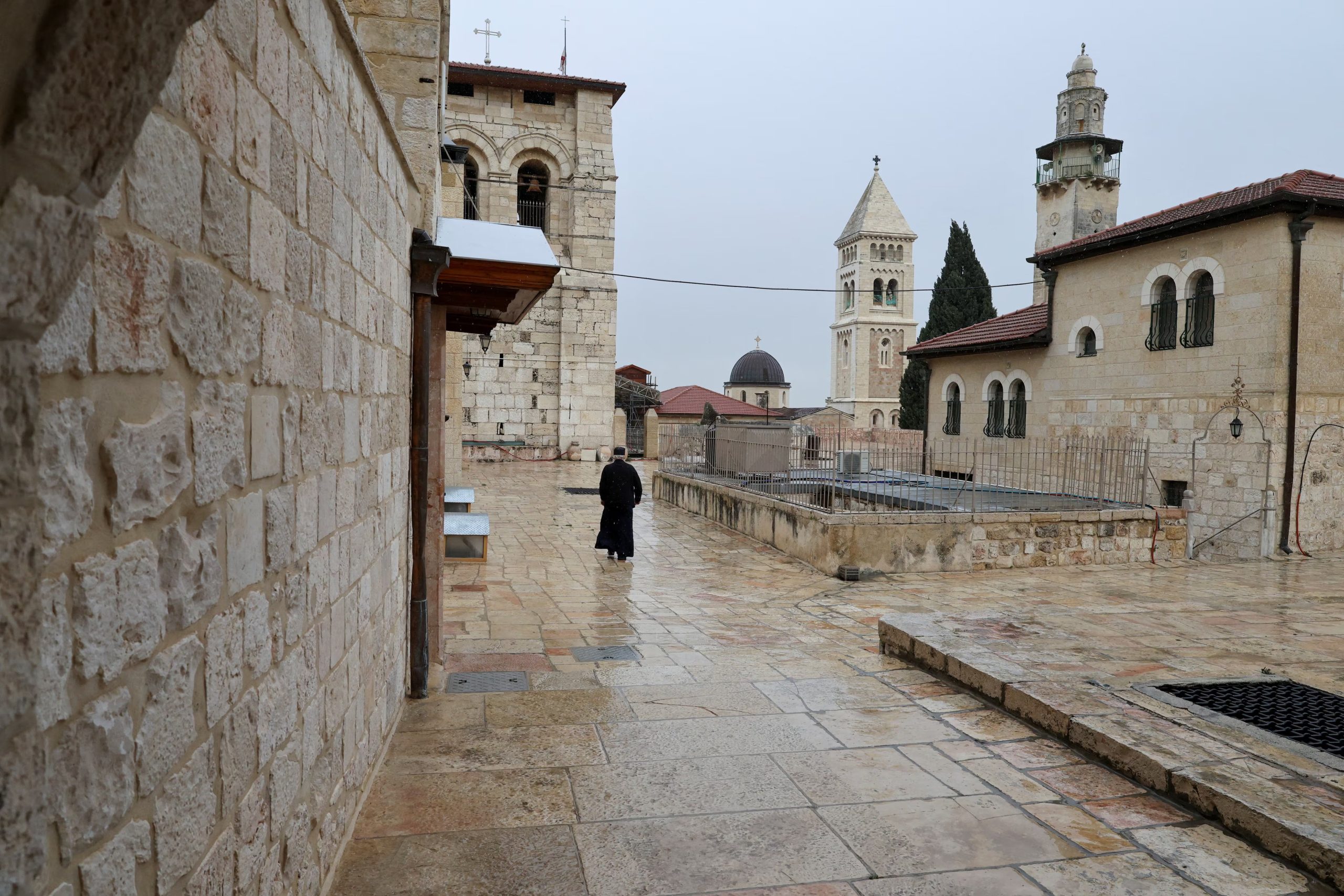 Una persona camina frente a la Iglesia del Santo Sepulcro, cerrada durante el Domingo de Ramos. Fragmentos de un misil iraní cayeron a pocos metros del templo en días recientes, según alegó Netanyahu para justificar las restricciones. (REUTERS/Ammar Awad)