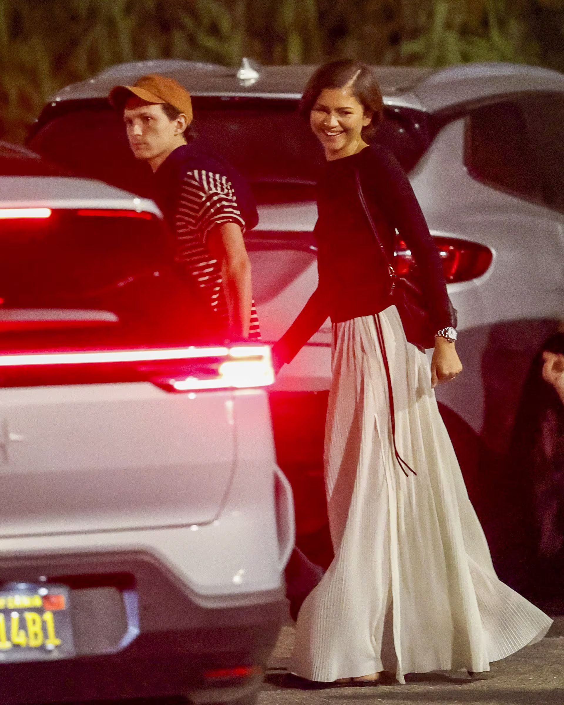 Zendaya con pollera larga blanca plisada y top oscuro de manga larga en una salida nocturna en Los Ángeles (The Grosby Group)