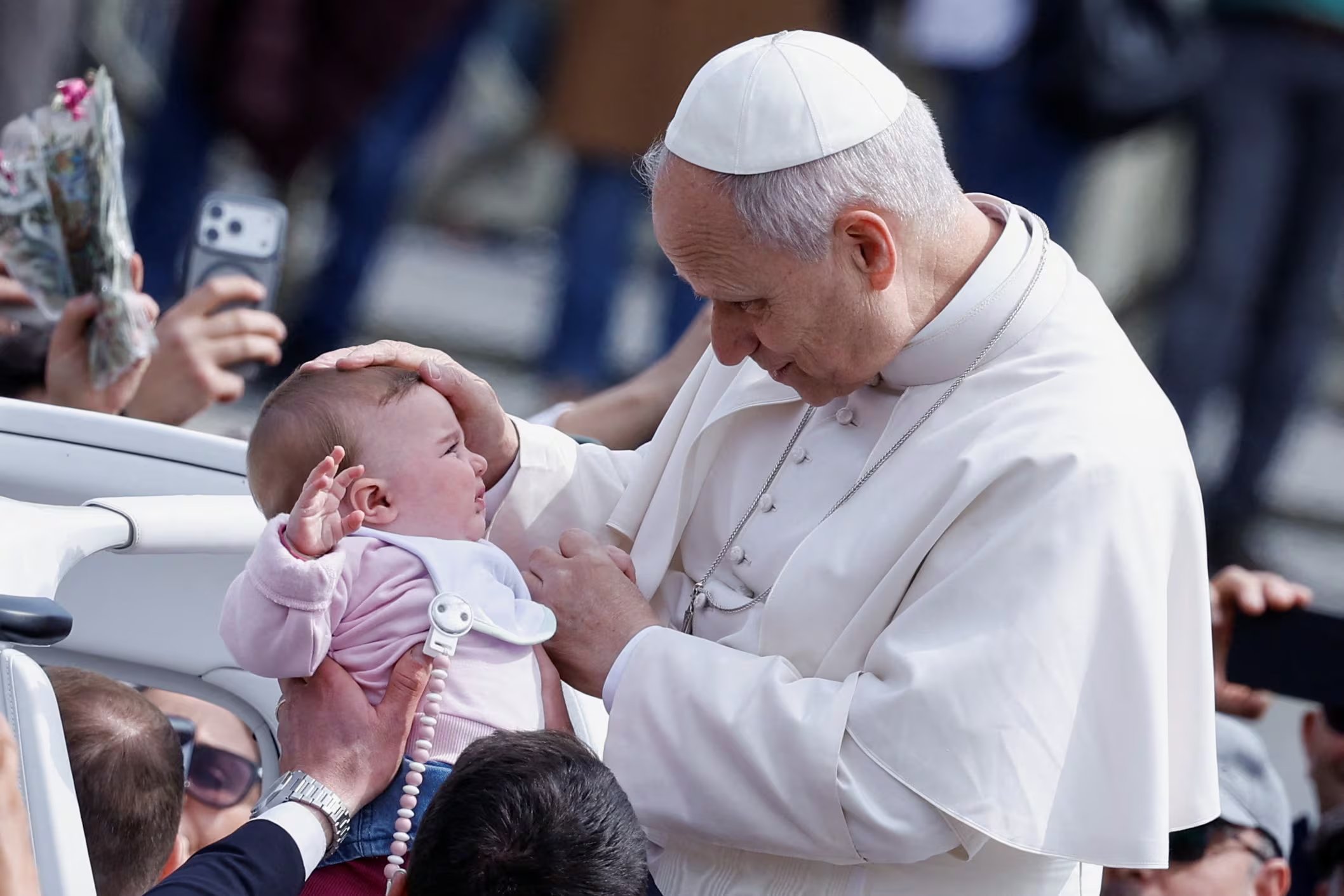 El papa León XIV bendice a un bebé al retirarse tras la misa del Domingo de Ramos en la Plaza de San Pedro. El pontífice pidió paz para los pueblos heridos por la guerra. (REUTERS/Remo Casilli)