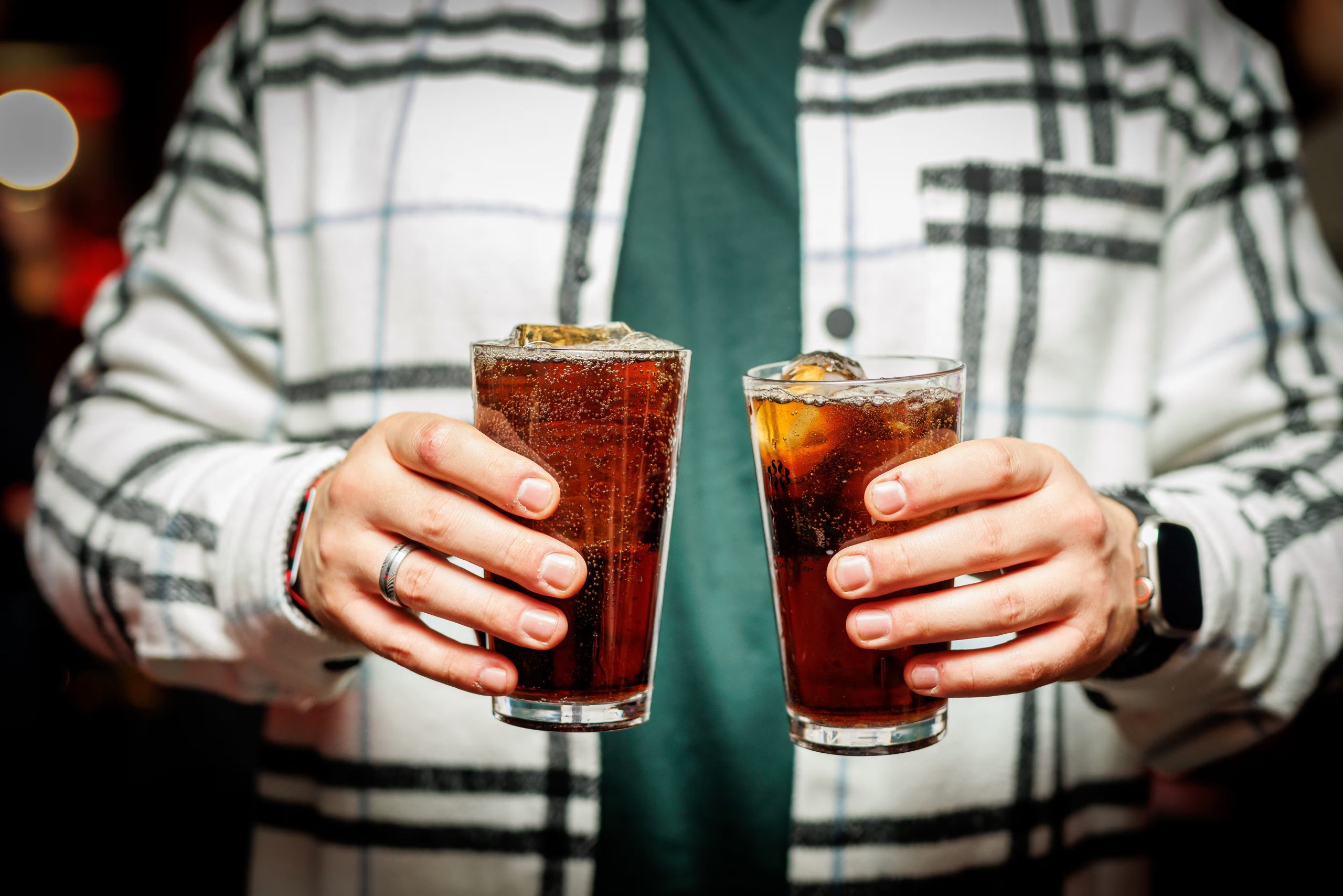 Un hombre con dos refrescos de cola (AdobeStock)