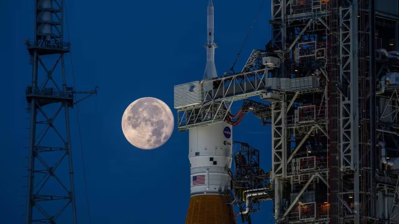 La luna llena se eleva sobre el cohete del programa Artemis II en la Plataforma de Lanzamiento 39B del Centro Espacial Kennedy, preparándose para una futura misión a la Luna. (Ben Smegelsky / NASA)